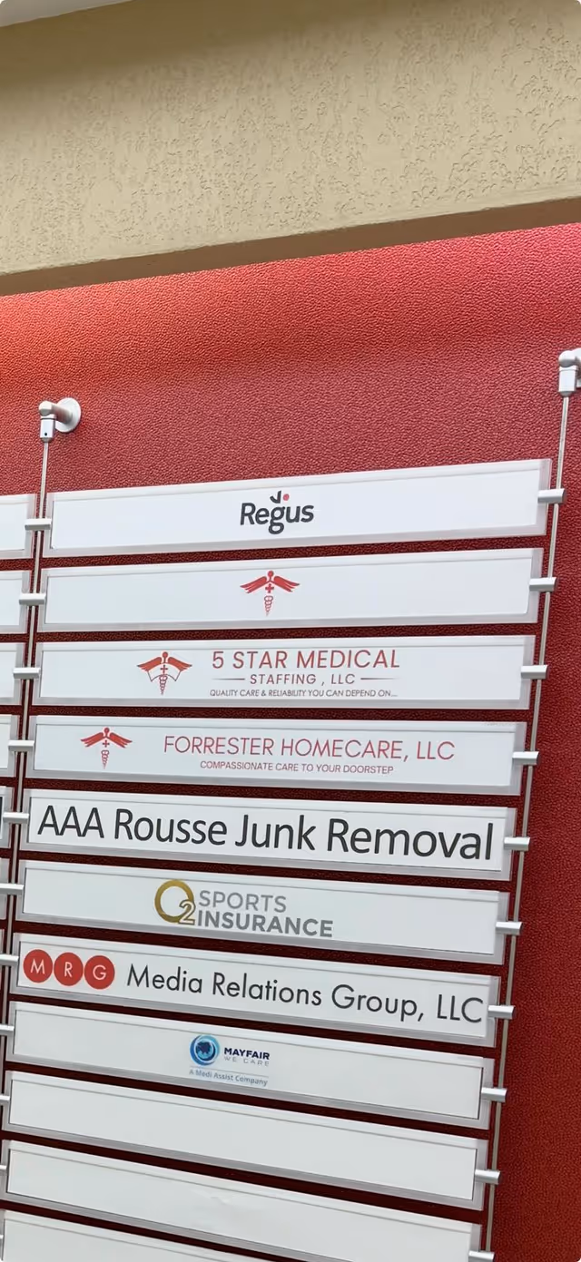 Vertical signboard displays multiple company names, including Forrester Homecare, against a red interior wall.