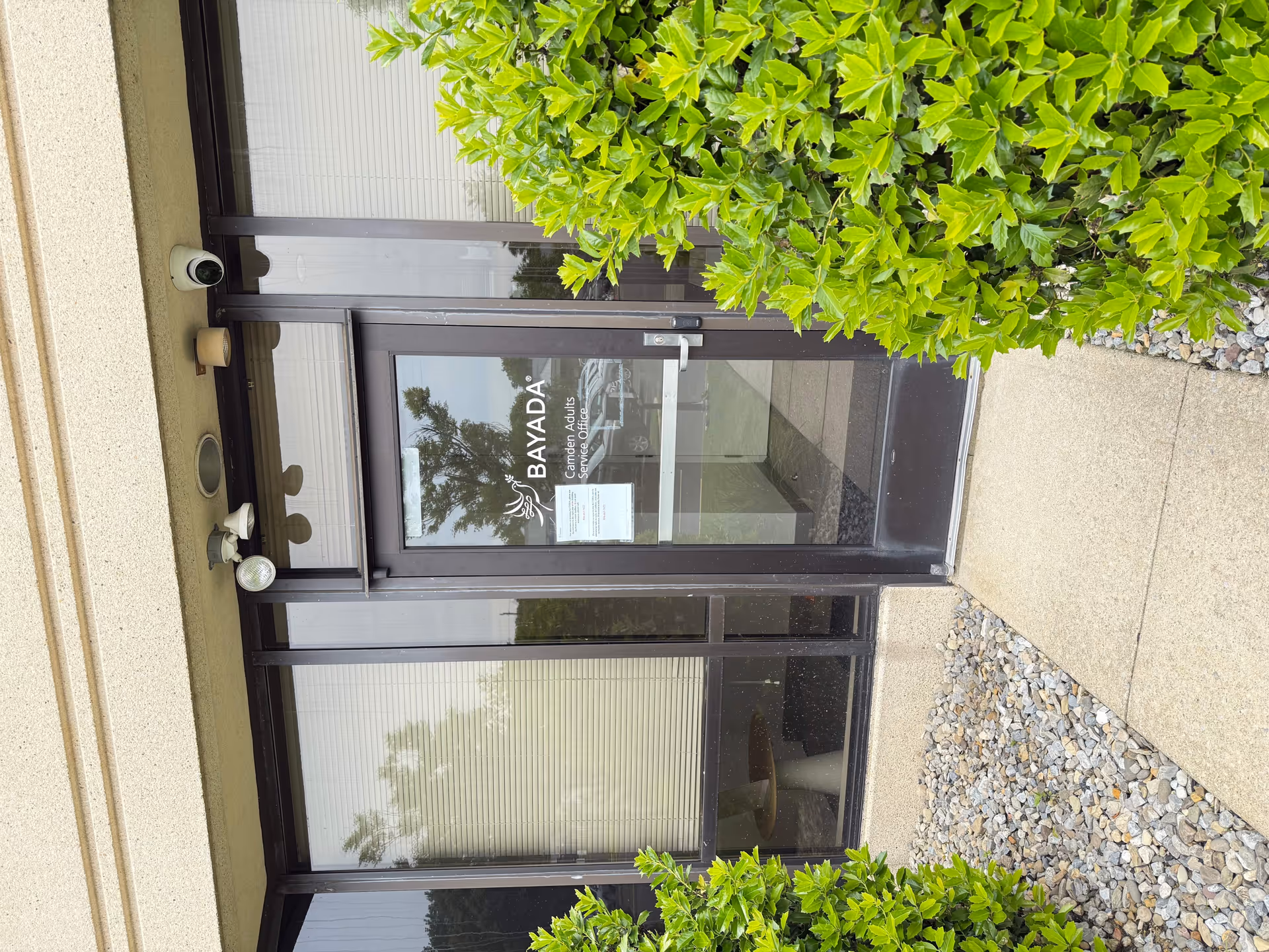 Front entrance of BAYADA Assistive Care with glass doors and surrounding greenery.