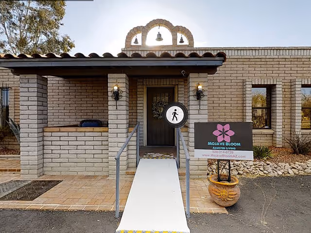 Exterior view of Mojave Bloom Assisted Living entrance with ramp, brick facade, and signage.