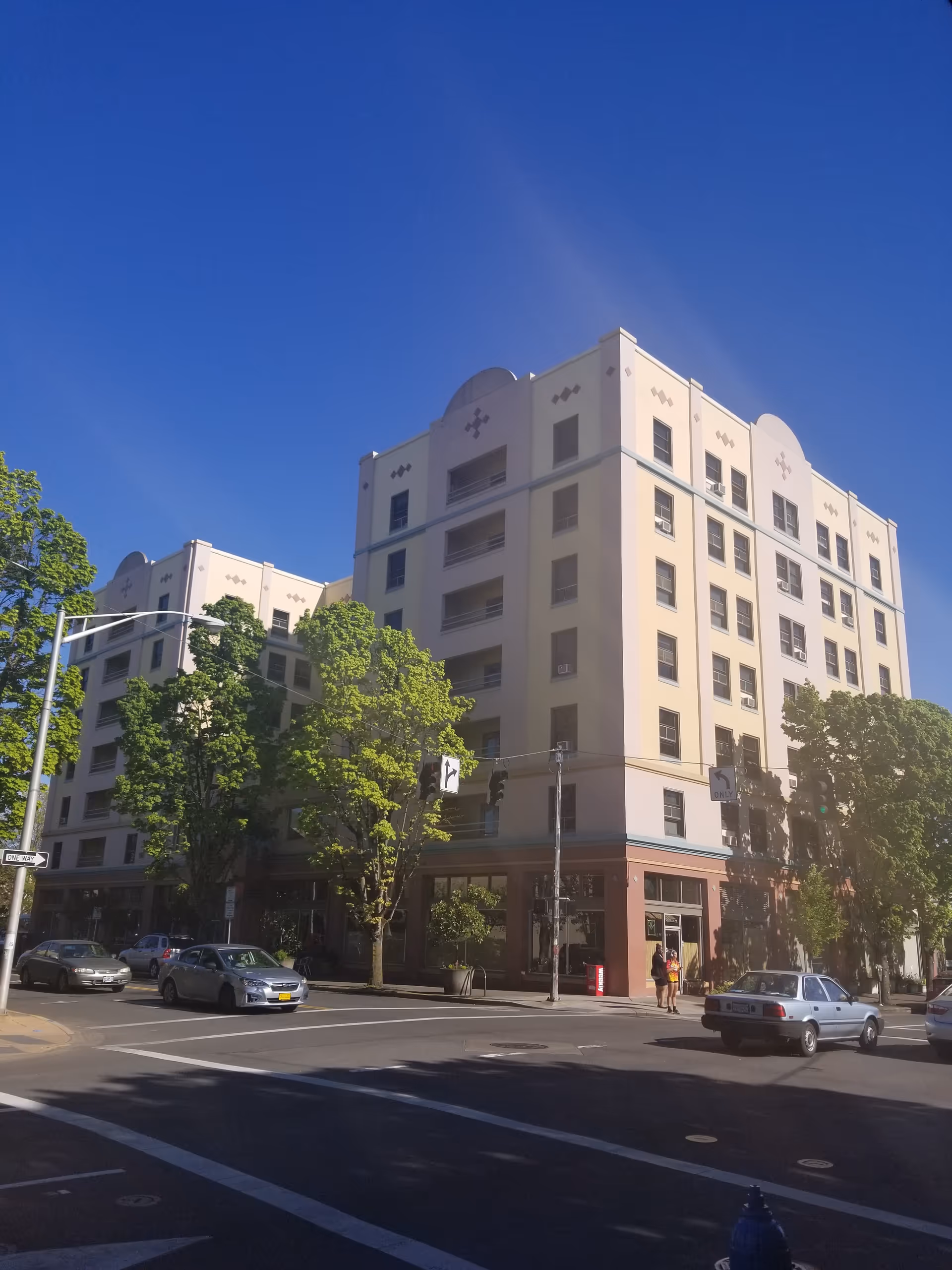 Exterior of The Eugene Hotel Retirement Community: a large light-colored multi-story building on a street corner.