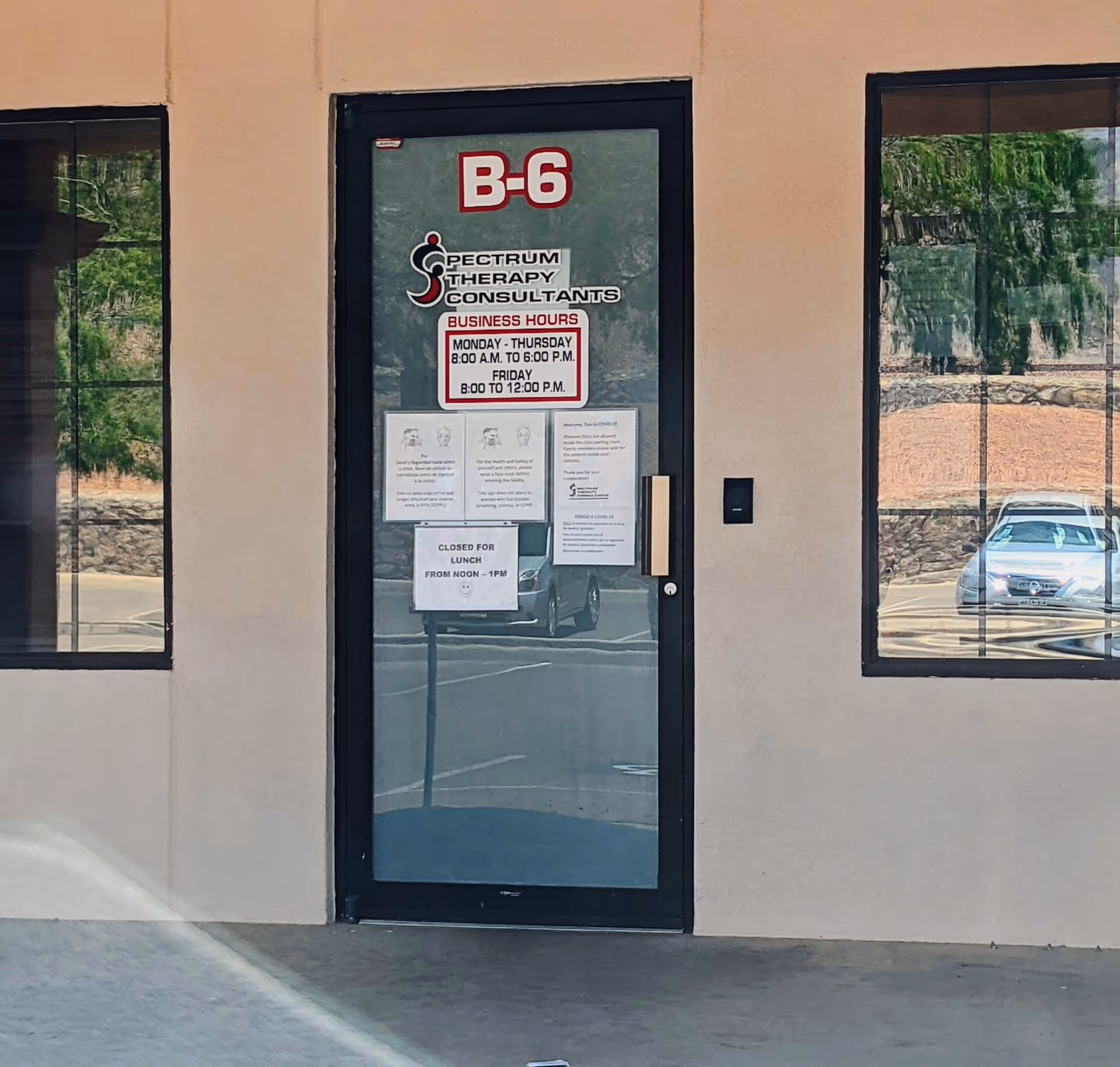 Glass door with Spectrum Therapy Consultants sign on a beige building exterior.