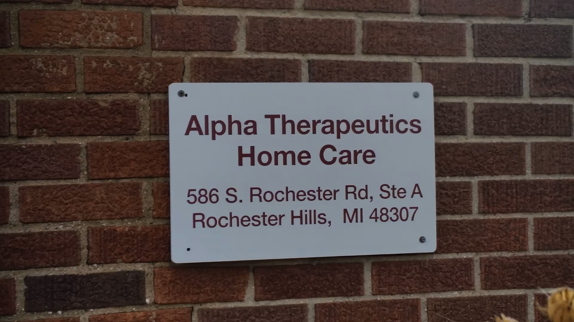 White sign mounted on brick wall reads Alpha Therapeutics Home Care.
