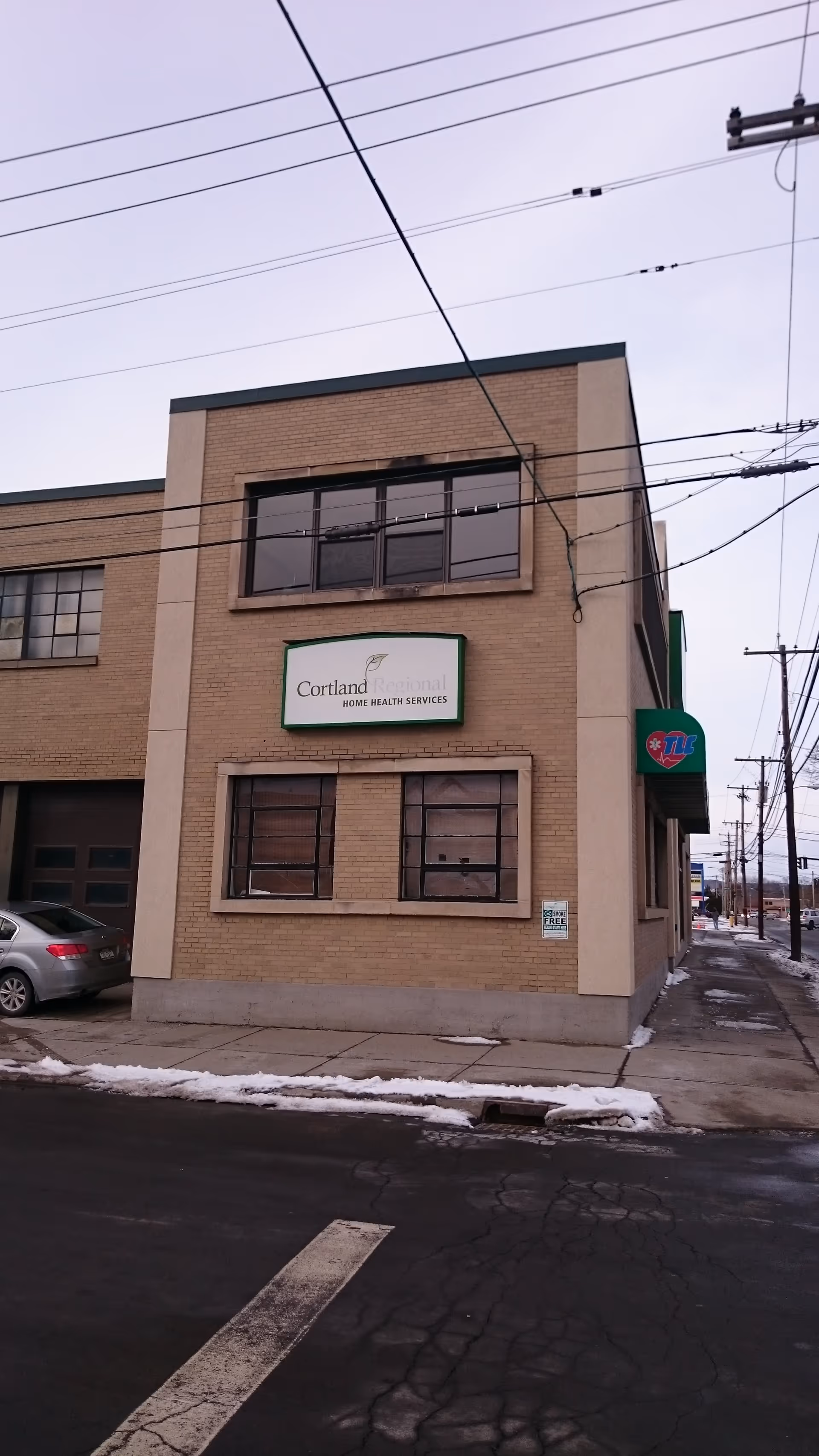 Brick building with Cortland Home Health Services sign on a snowy street.