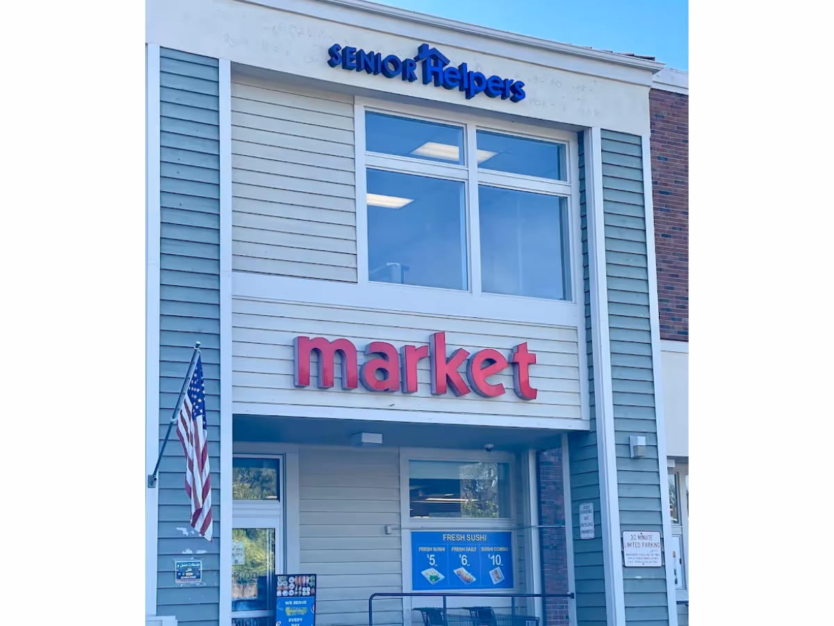 Exterior storefront with a large red market sign and American flag.