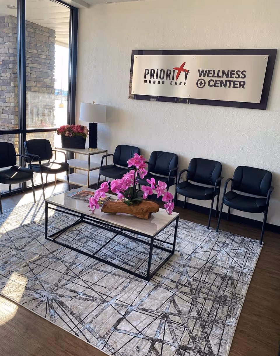 Lobby seating area with black chairs, glass coffee table, and a sign reading Priority Wound Care.