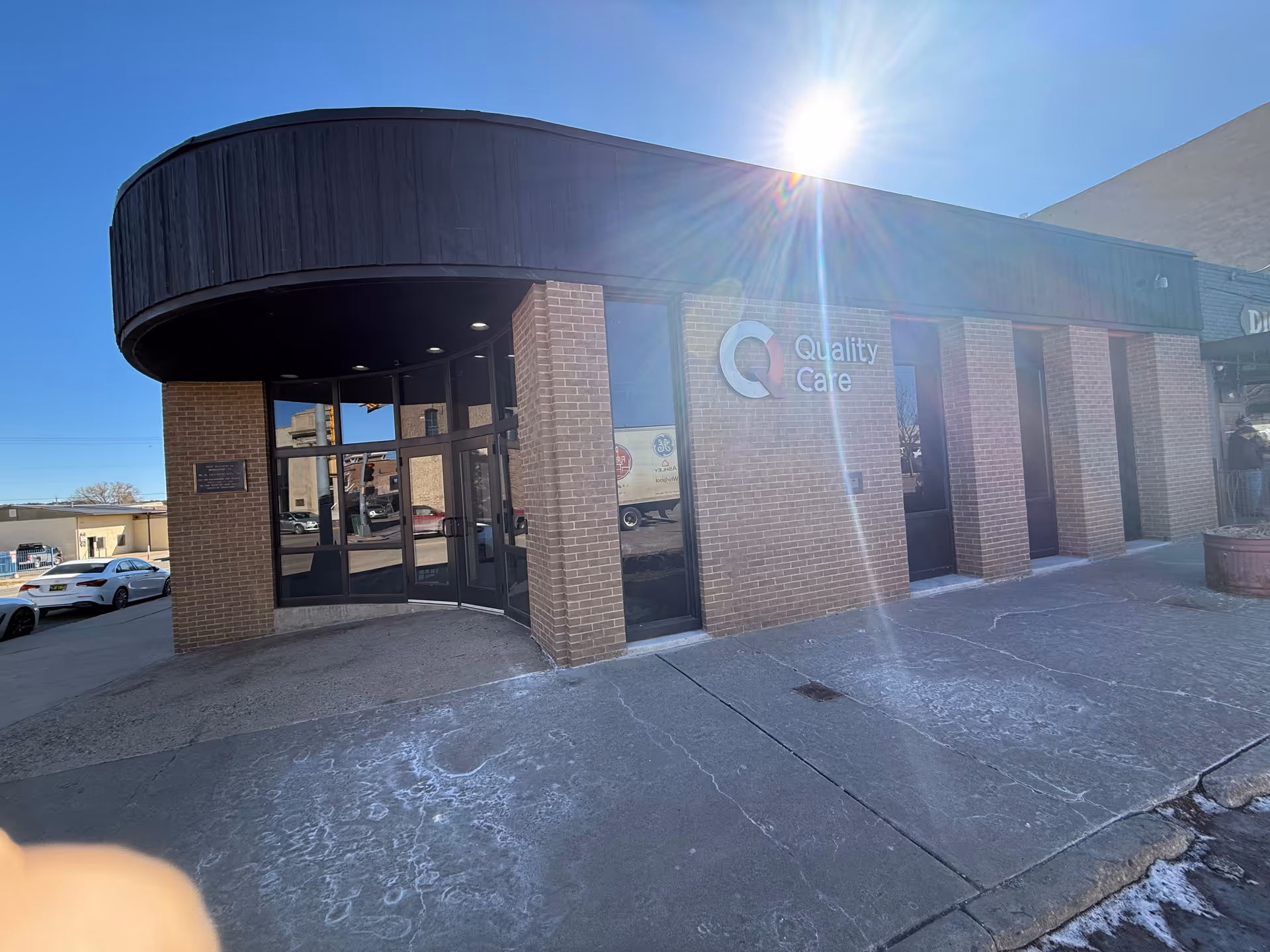 Brick-front building with curved black awning and glass entrance marked 'Quality Care'.