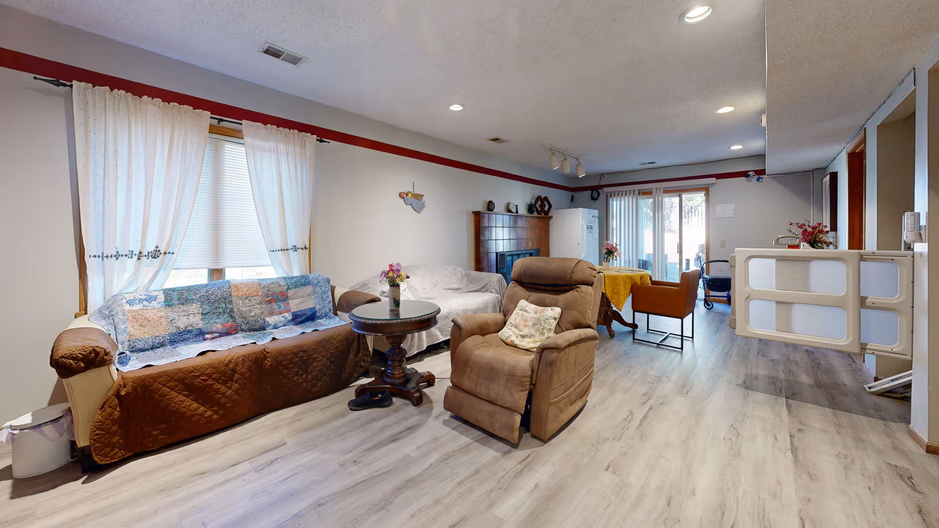 Cozy senior living common area with sofa, armchair, coffee table, and sliding doors.