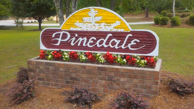 Entrance sign for Pinedale Residential Center with a brick planter and flowers.