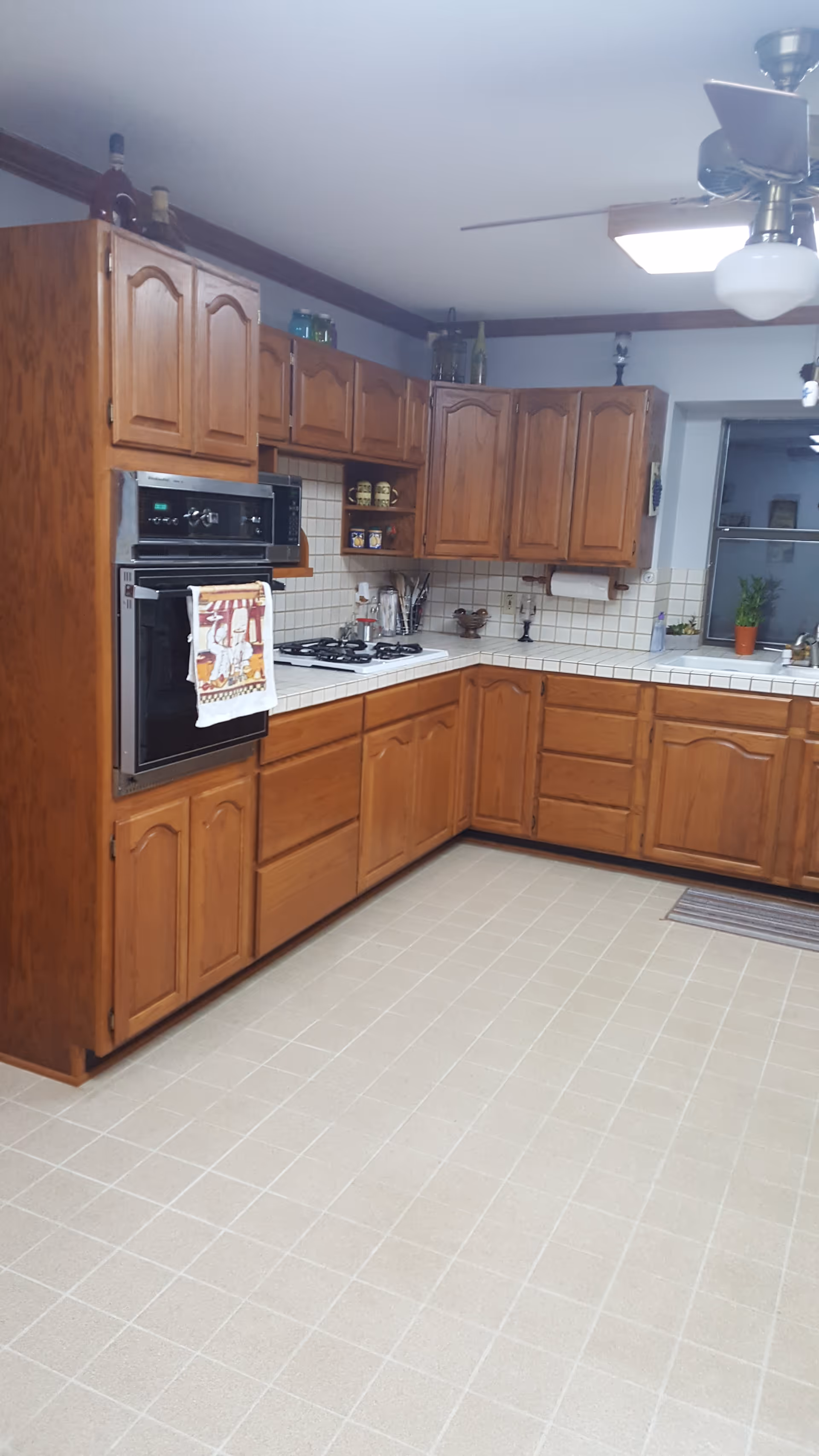Bright kitchen with wooden cabinets, stove, and tiled countertops in a senior facility.