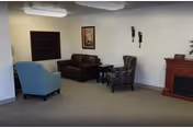 Cozy living area featuring blue chair, brown sofa, fireplace, and wall art.