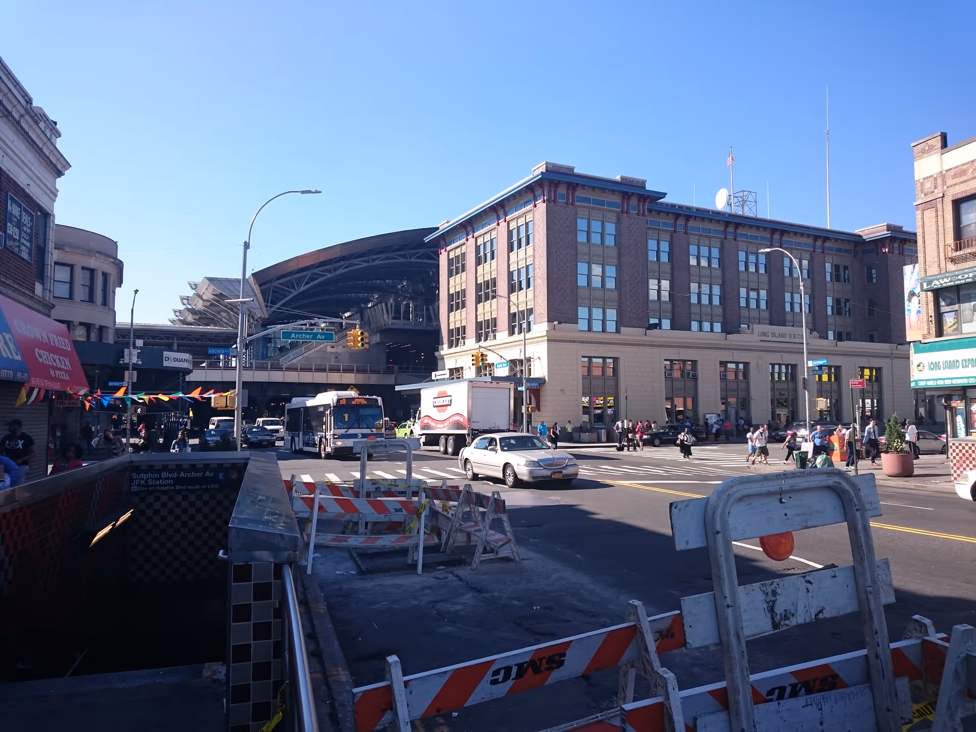 Busy urban street scene with a brick building and pedestrians.
