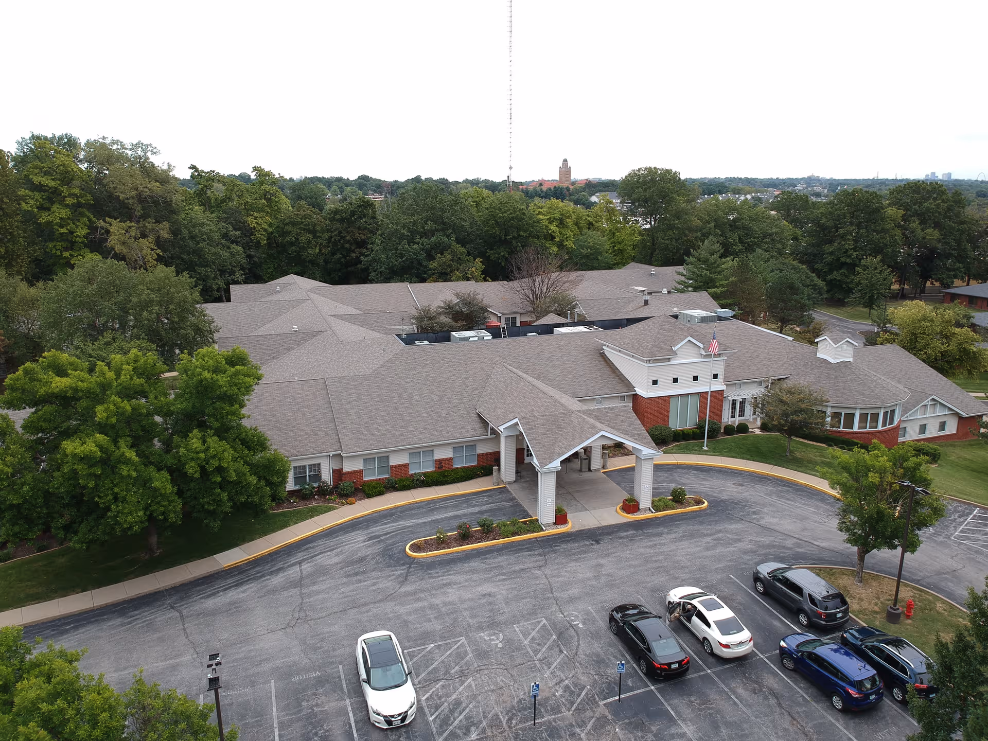 Aerial view of Cardinal Ritter Senior Services building with driveway, parking, and trees.