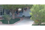 Exterior view of a senior living facility front entrance with trees and landscaping.