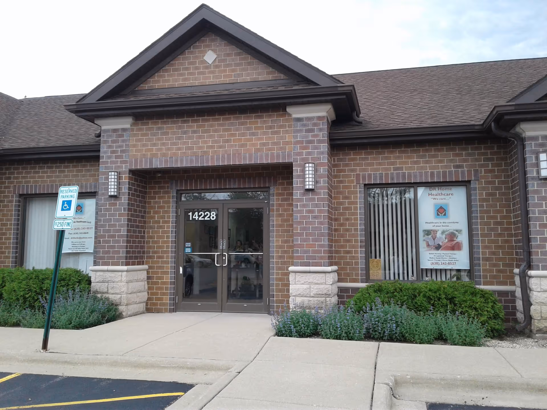 Brick medical facility entrance with glass doors, address 14228, DR Home Healthcare signage, and shrubs.