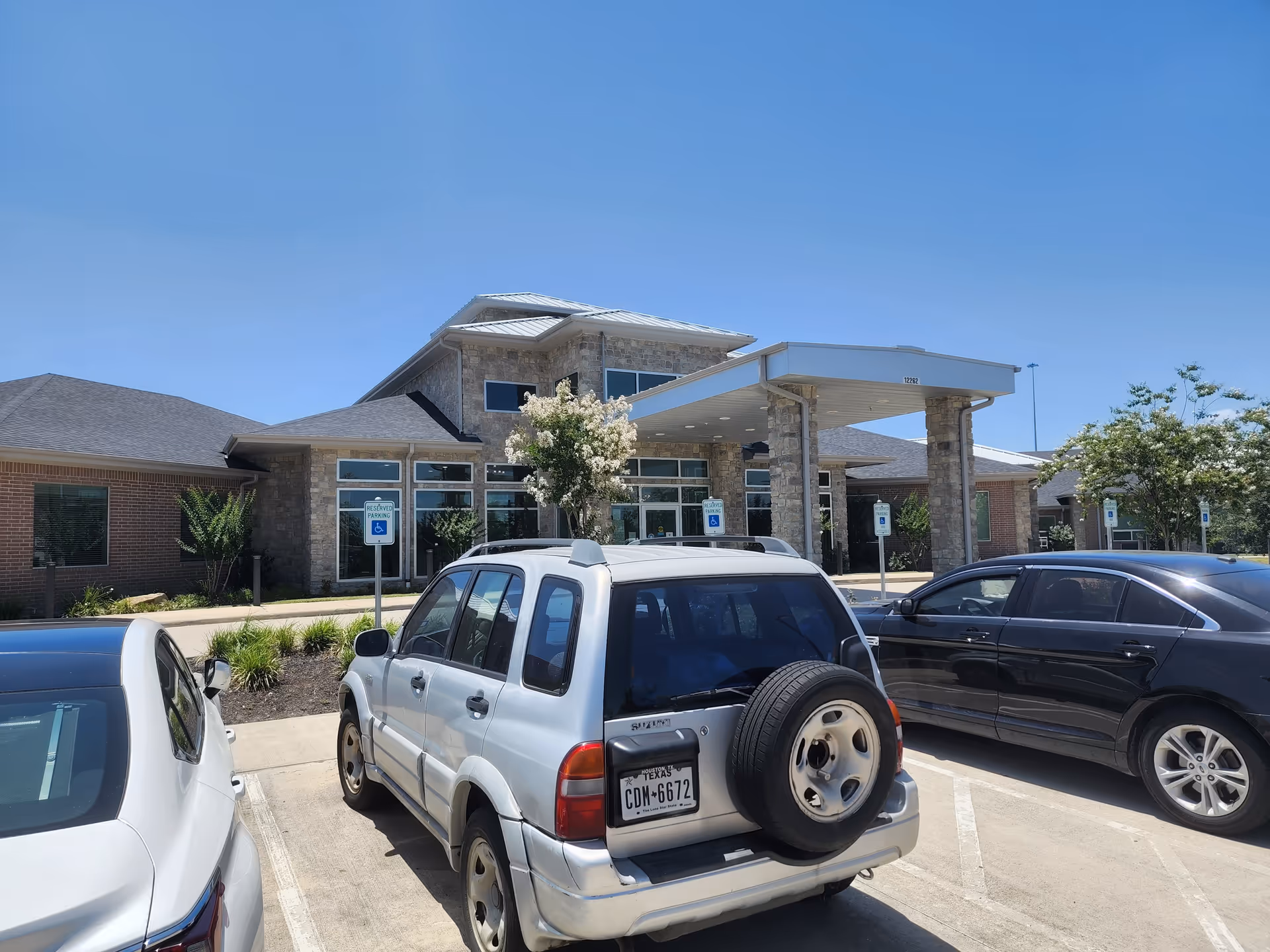 Terra Bella Health and Wellness Suites building exterior with a vehicle-filled parking lot and entrance canopy.