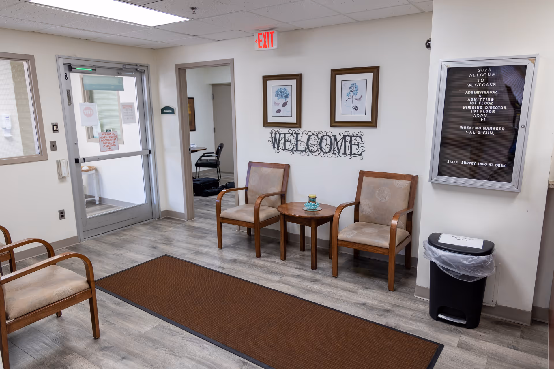 Lobby waiting area with chairs, a small table, and 'WELCOME' wall art.