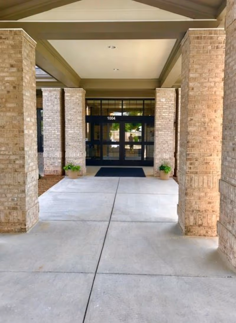 Covered entrance with brick columns leading to glass double doors marked "1004".