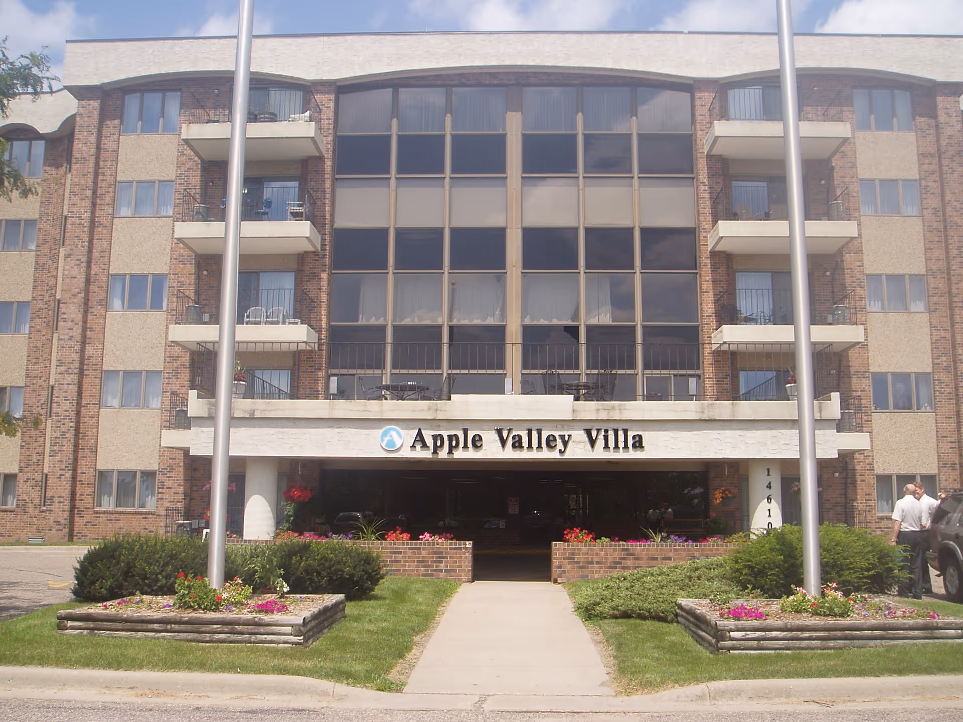 Front exterior of Apple Valley Villa senior living building with balconies and central entrance