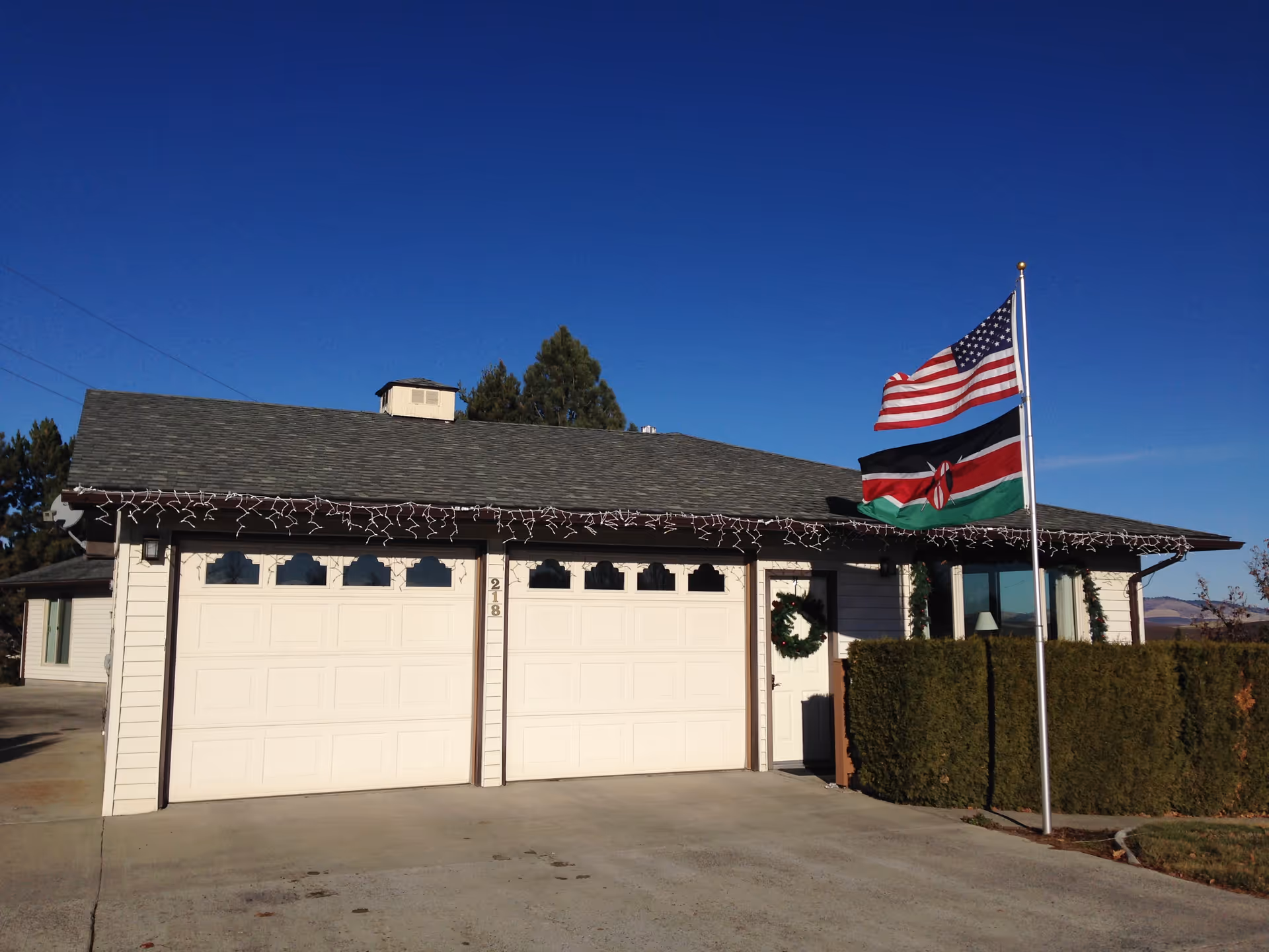 Front of a single-story house-style facility with two garage doors and flags.