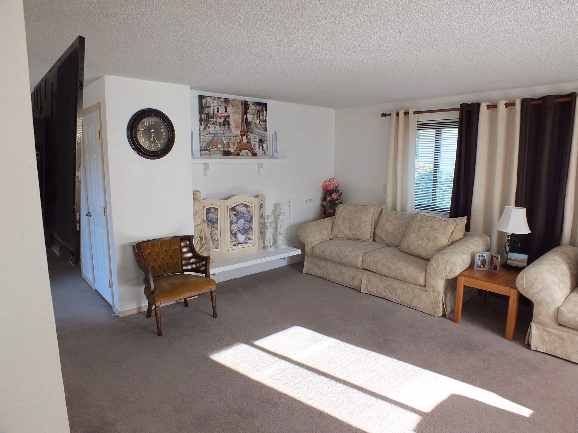 Cozy living room with beige sofa, chair, lamps, a window with curtains.