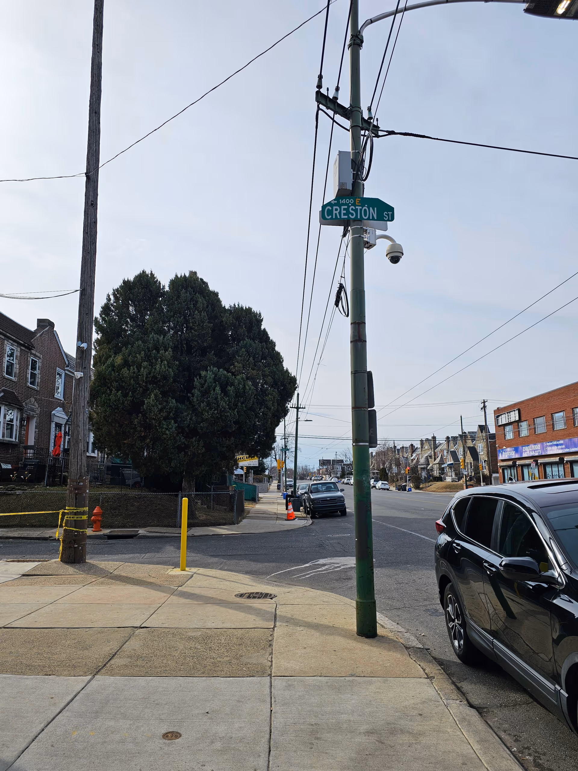 Urban street scene with crosswalk, parked cars, and Creston Street sign.