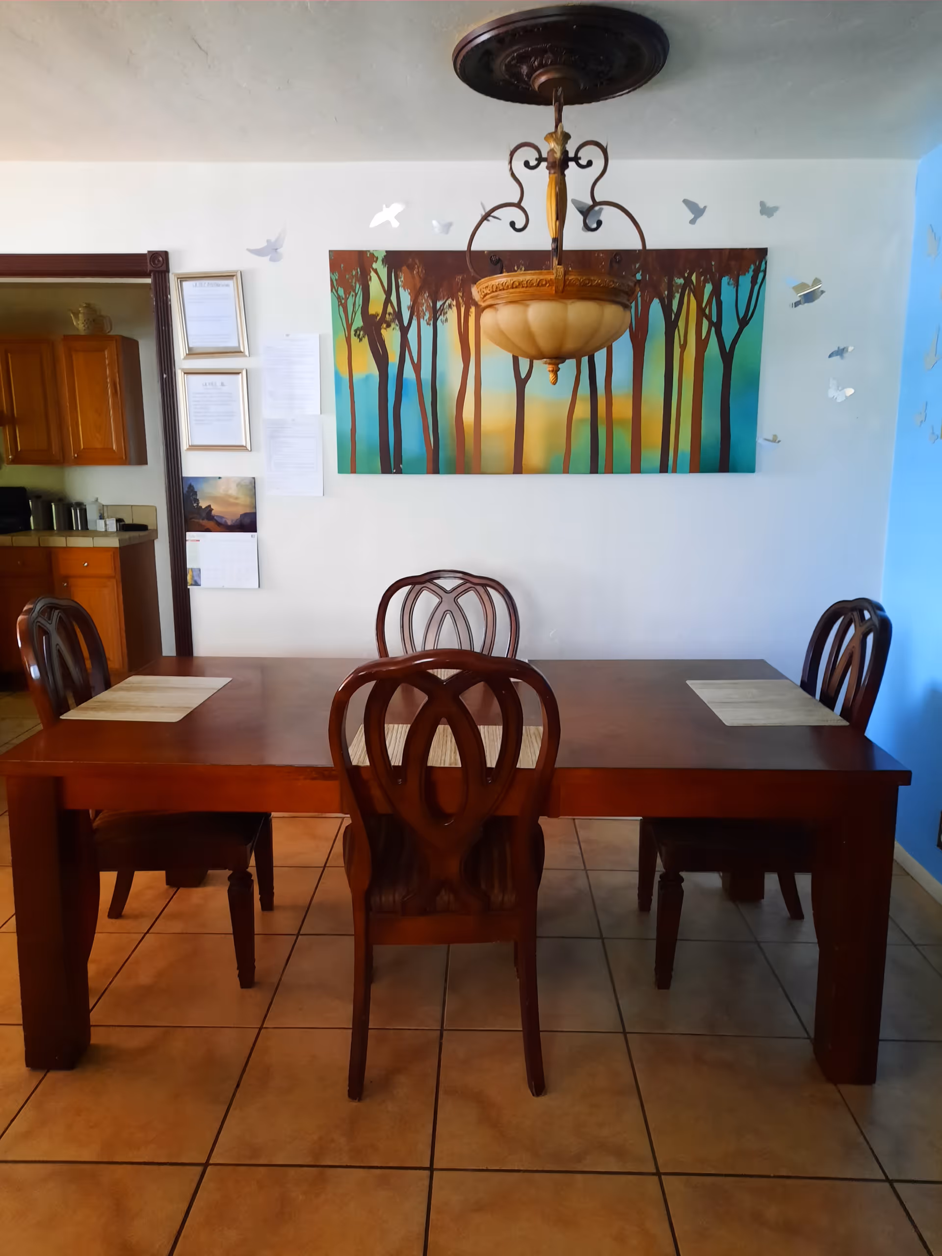 A wooden dining table with four chairs in a bright assisted living dining room.