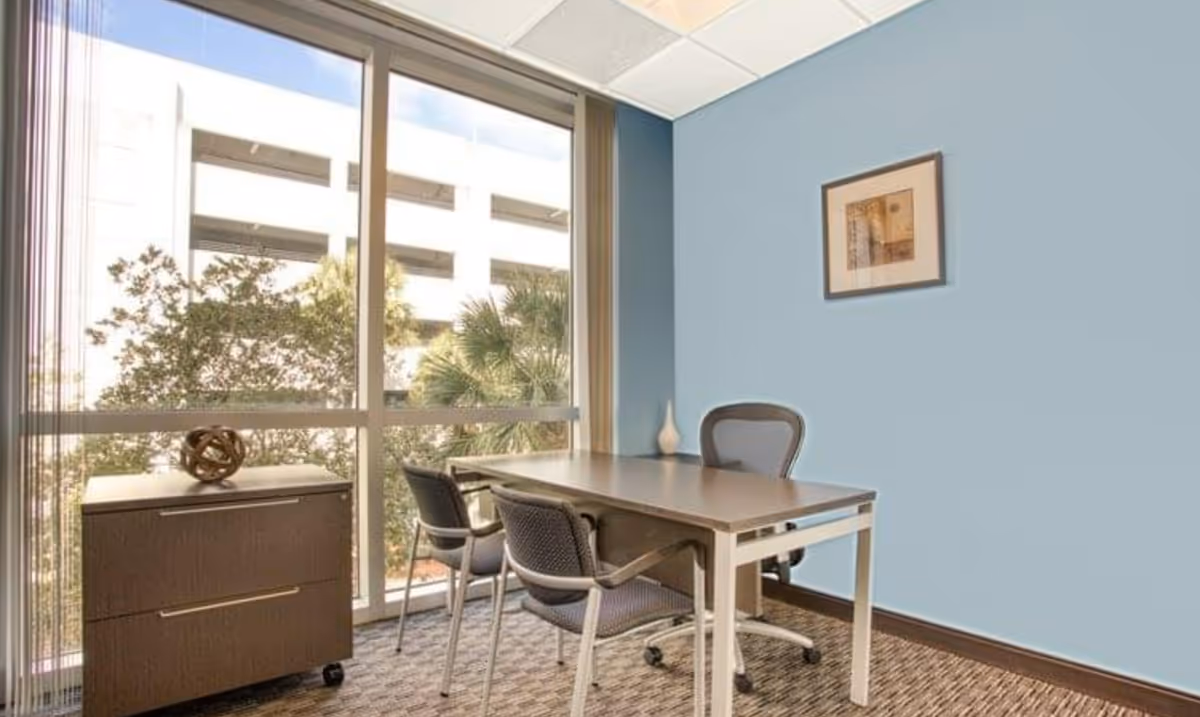 Small meeting room with desk, chairs, and a large window.