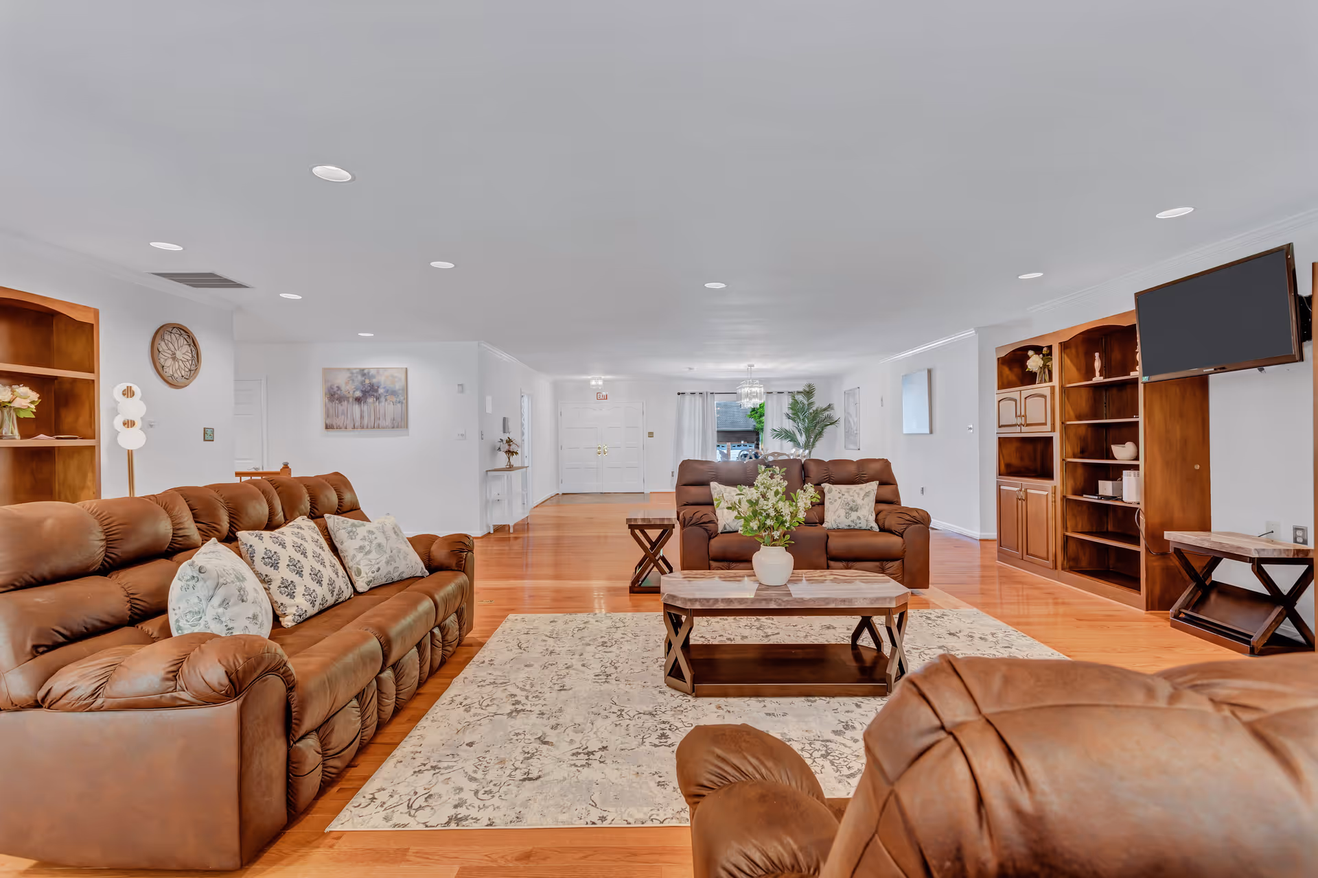Bright living room in a senior facility featuring brown leather sofas and a TV.