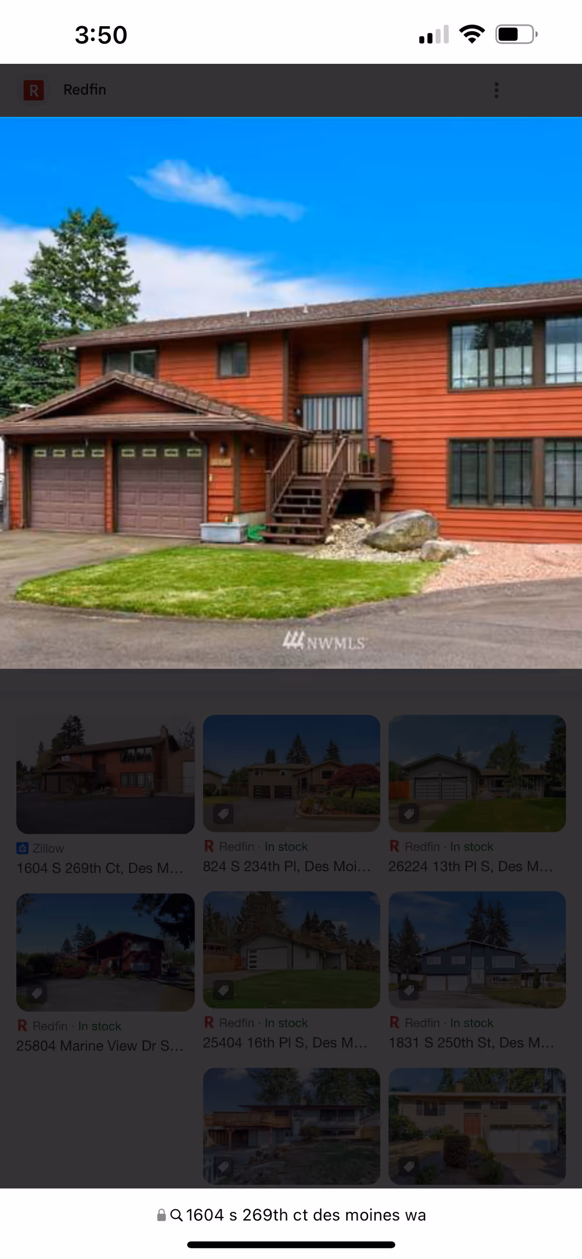 Red-brown two-story building exterior with garage doors and stairs.