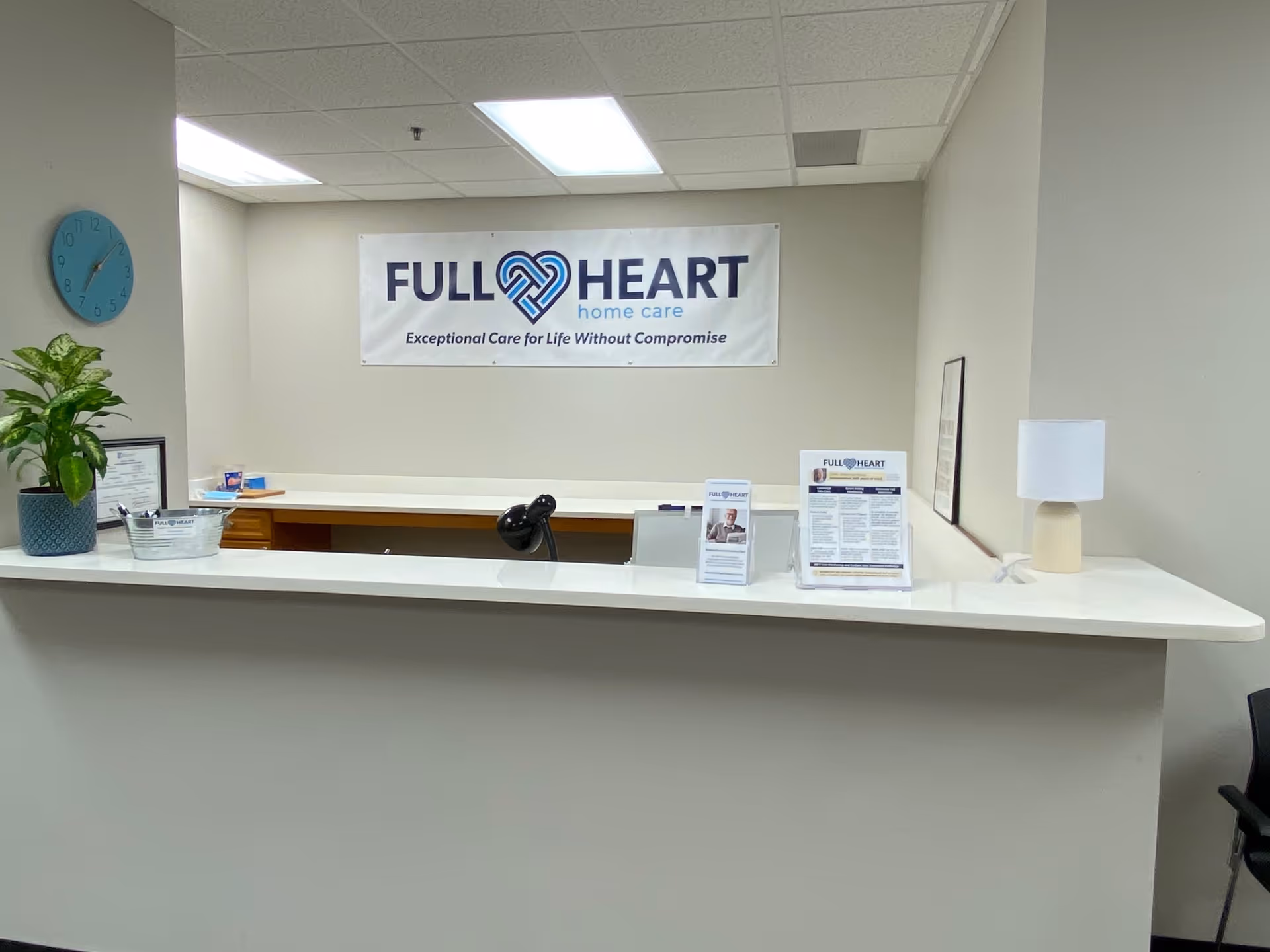 Interior reception area featuring a counter, Full Heart Home Care banner, and a plant.