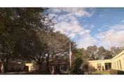Wide view of a tan senior living center exterior with trees and blue sky