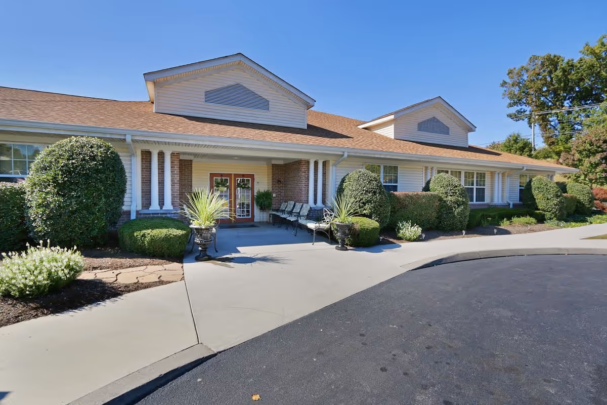 Single-story senior living facility entrance with landscaped bushes along the front