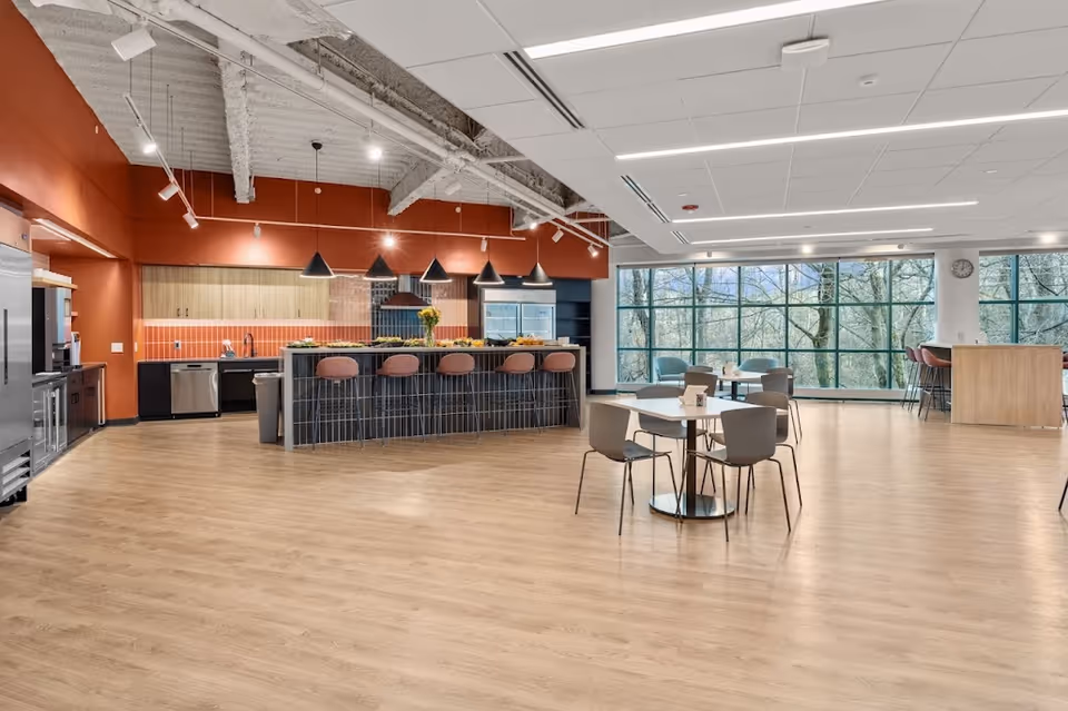 Spacious senior living dining area with a kitchen bar, wood floors, and large windows.