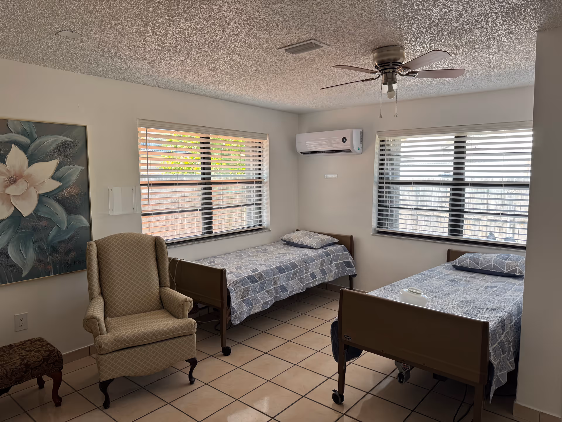 Two single beds with blue checkered bedding sit in a bright shared bedroom.