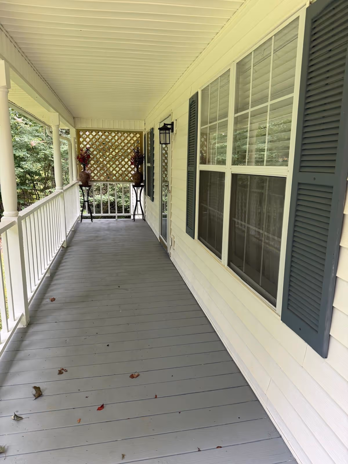 Covered porch along the facility with railing, windows, and decorative planters.
