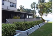 Exterior view of Presbyterian Villas of Tampa with a walkway, hedges, and palm trees.