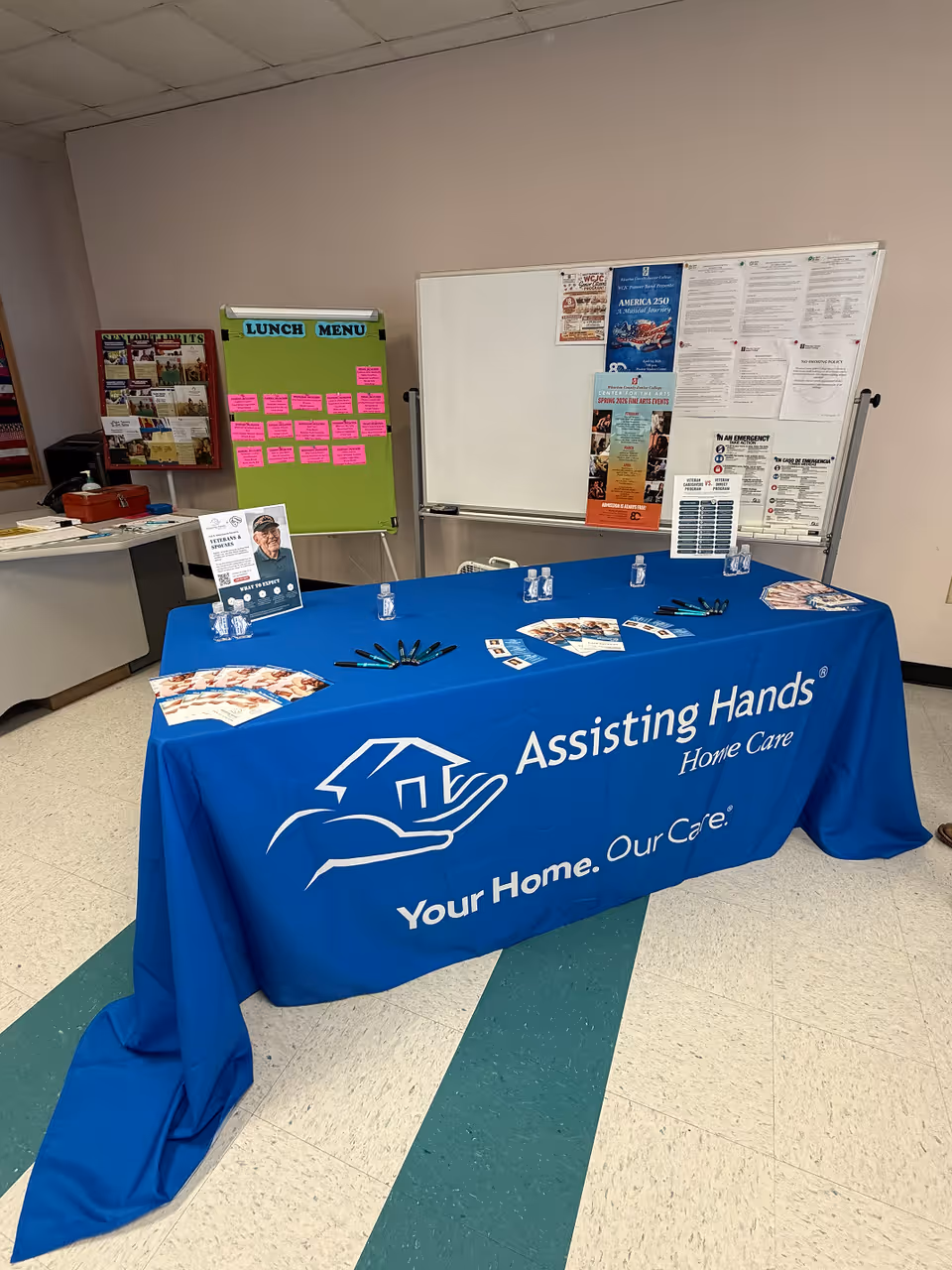 Blue-covered table with Assisting Hands Home Care branding sits in an interior facility.
