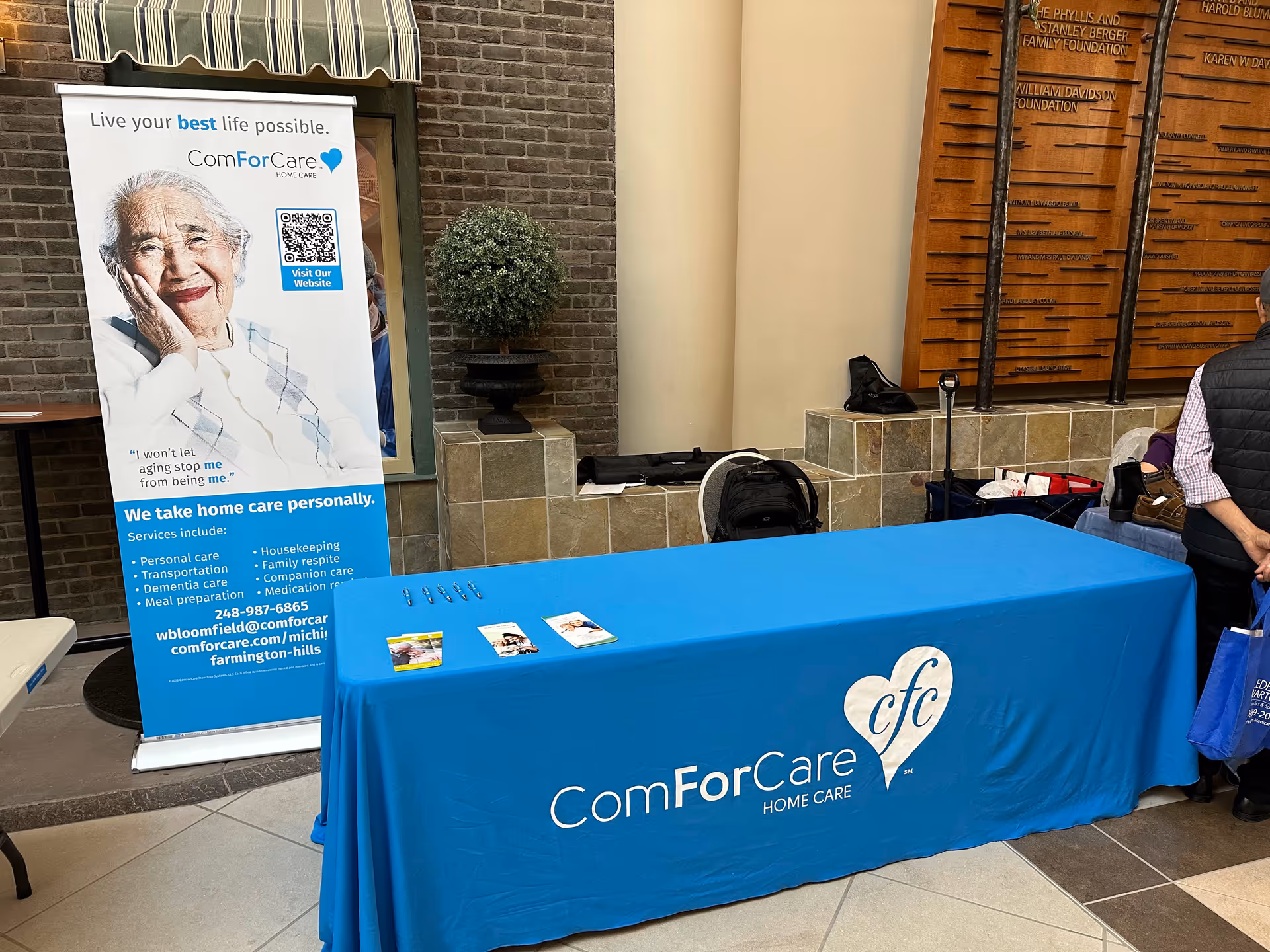 Indoor lobby table with blue ComForCare banner and promotional materials.
