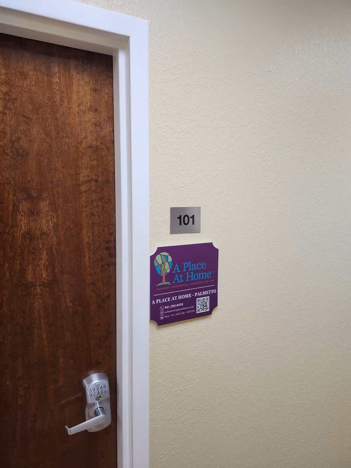 Wooden door labeled 101 with a purple A Place At Home sign beside it.