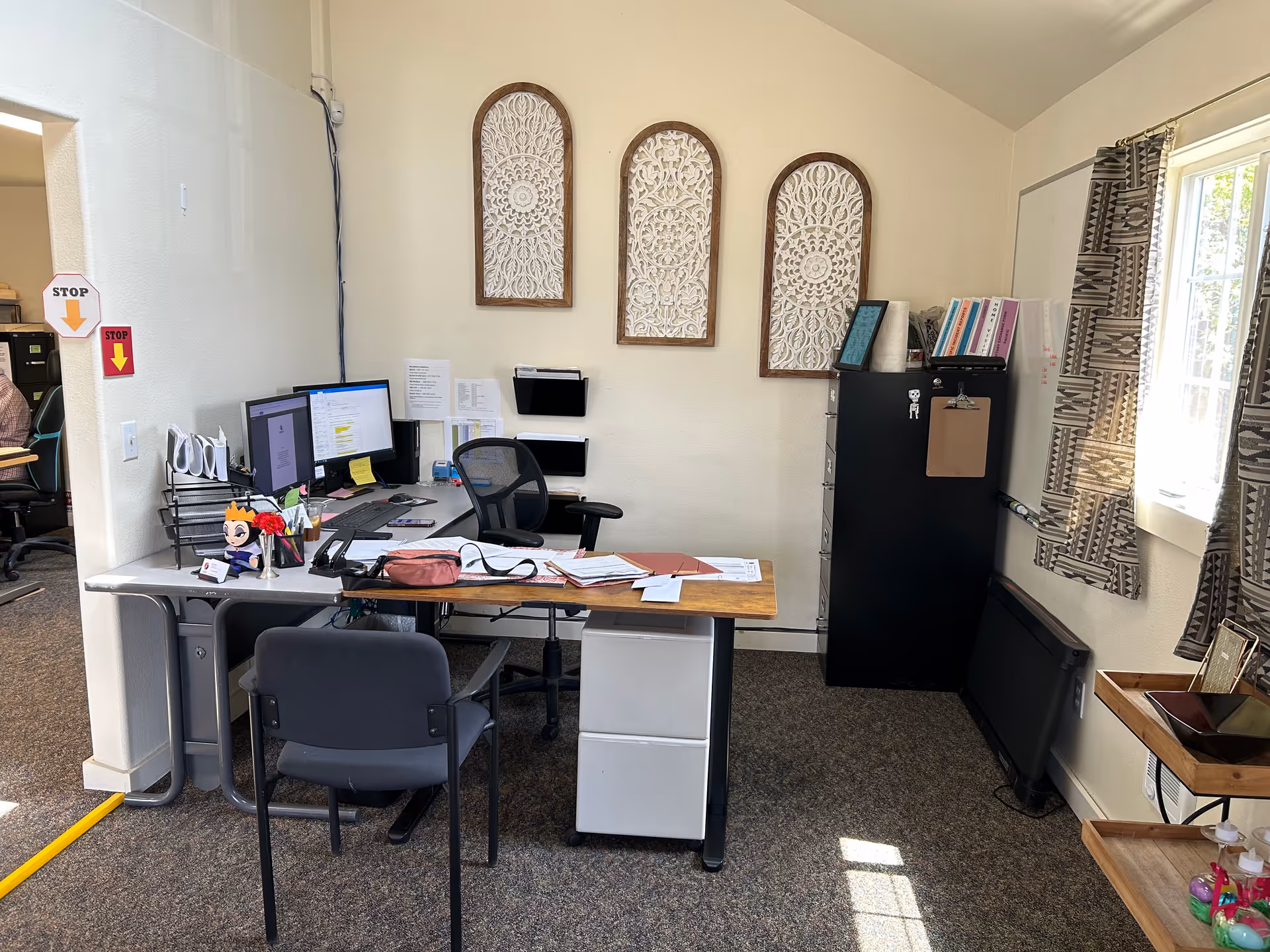 Office desk with computers, filing cabinet, and decorative arches in a senior care facility.