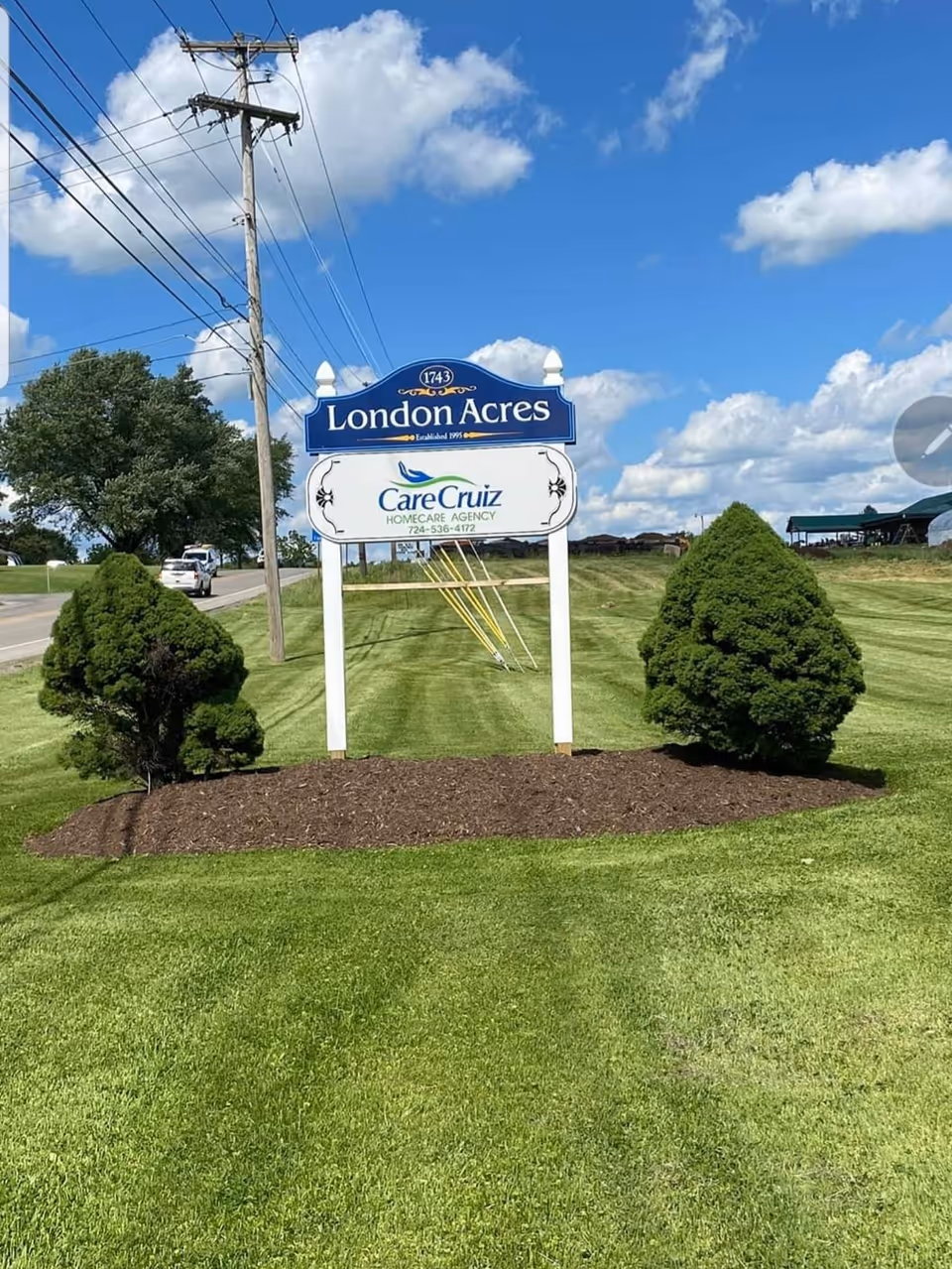 Exterior sign for London Acres and CareCruiz Homecare Agency LLC on a lot beside a road.