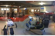 Interior facility gym area with exercise equipment and a red car on display.