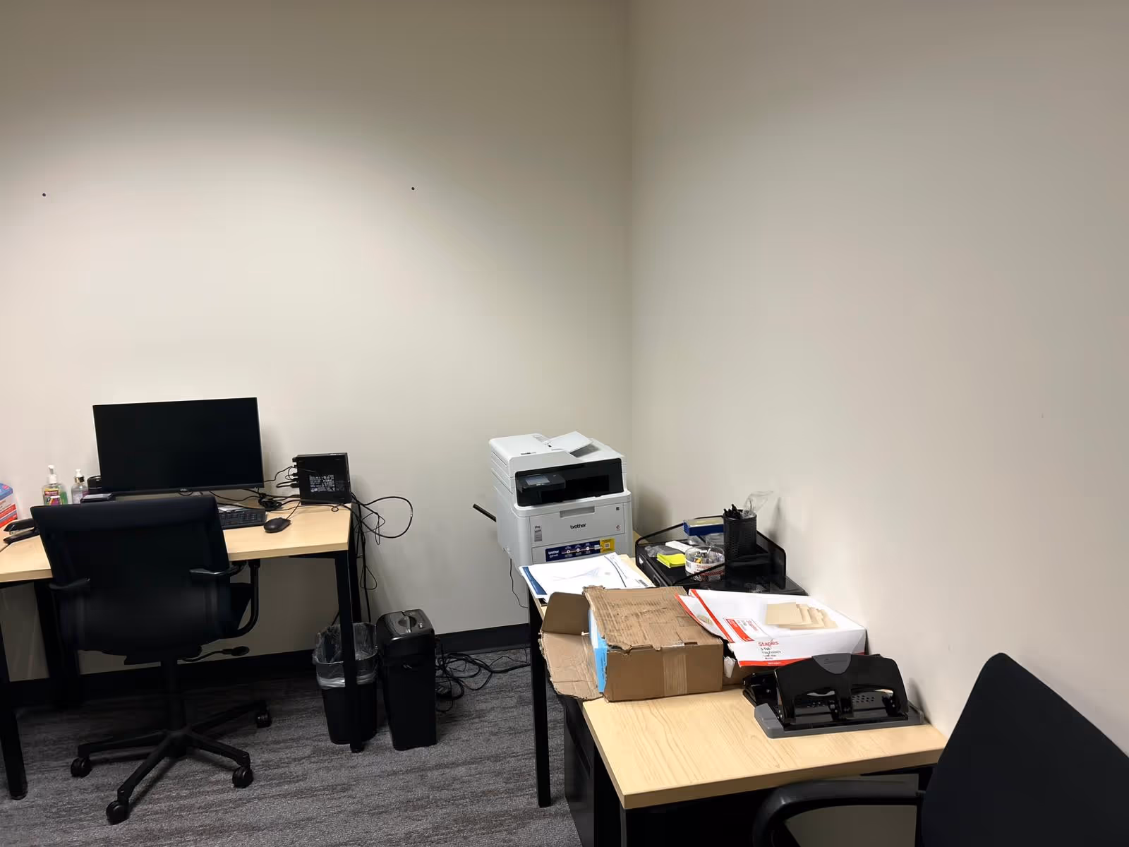 Interior office with a computer, printer, and scattered boxes on desks.