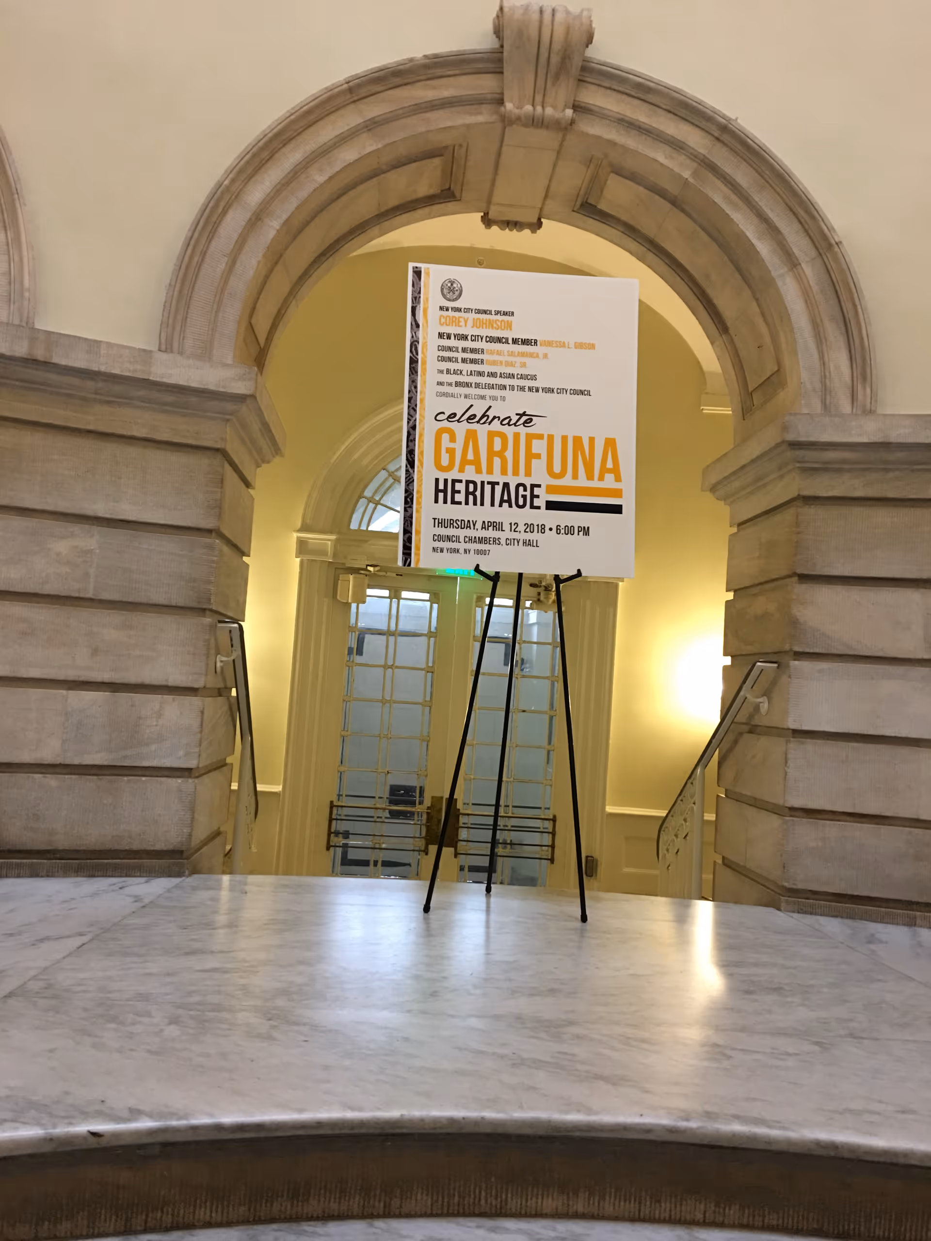 Elegant stone archway and a poster on a stand inside a marble lobby.