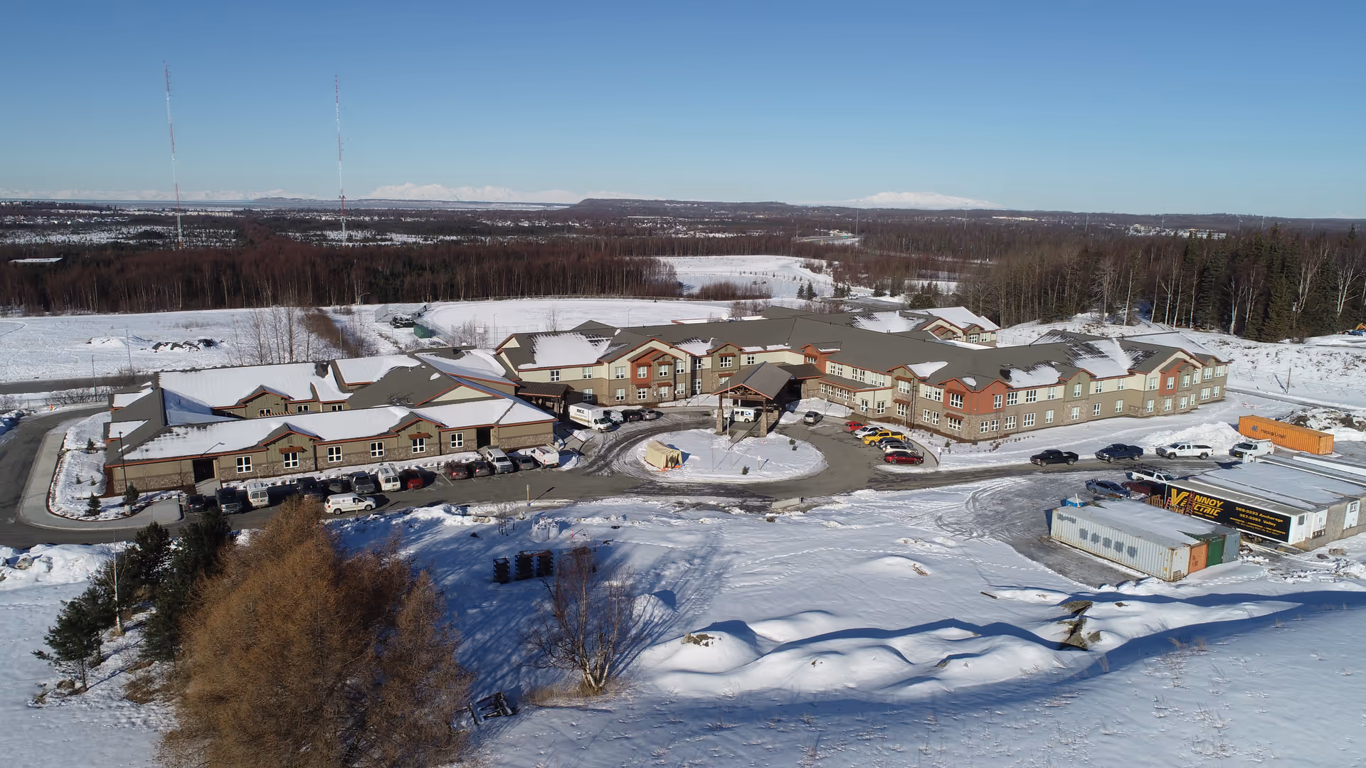 Aerial view of a snow-covered senior living campus with connected buildings and parking.