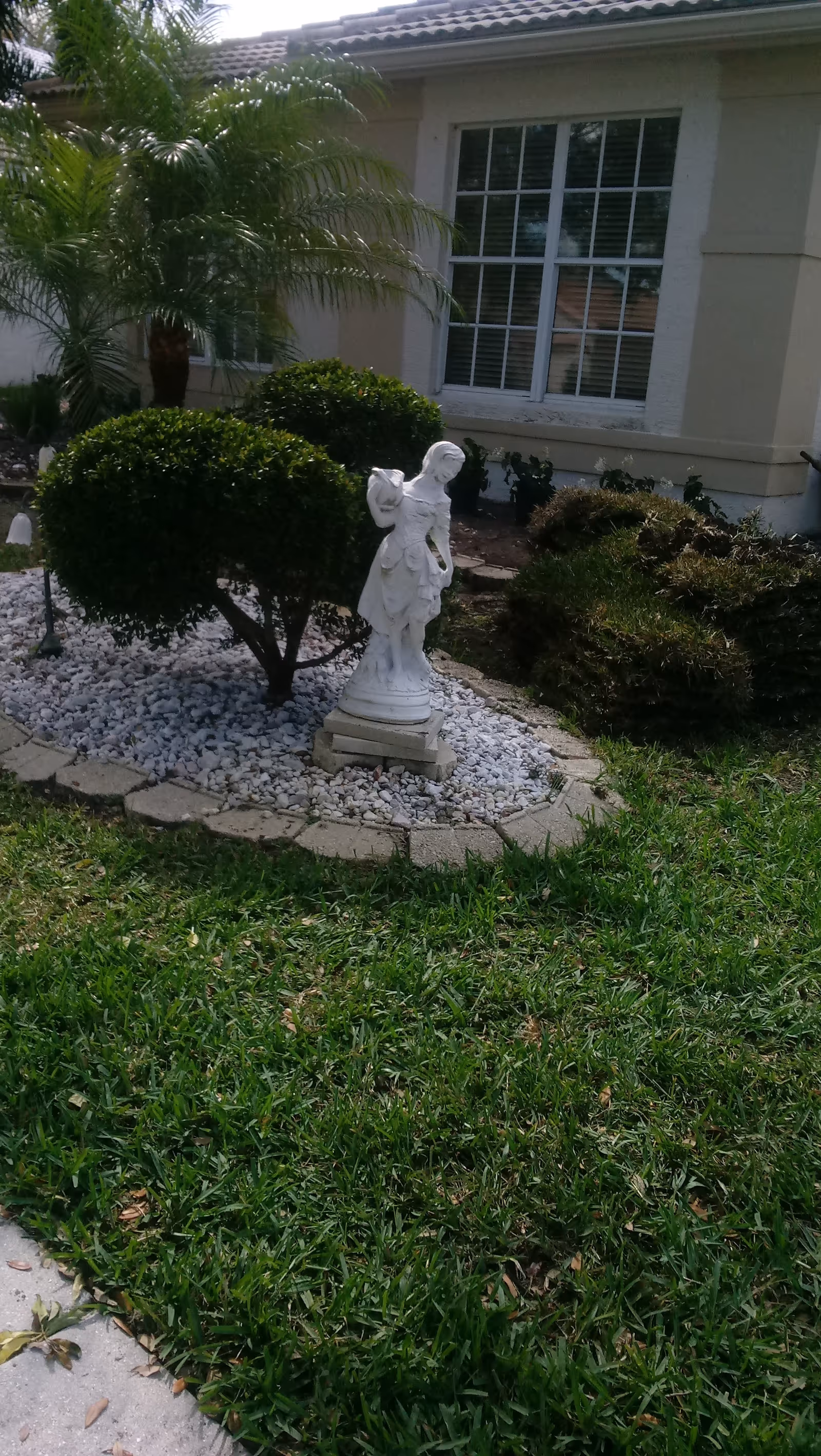White garden statue amid shrubs in front of Valencia Isles building.