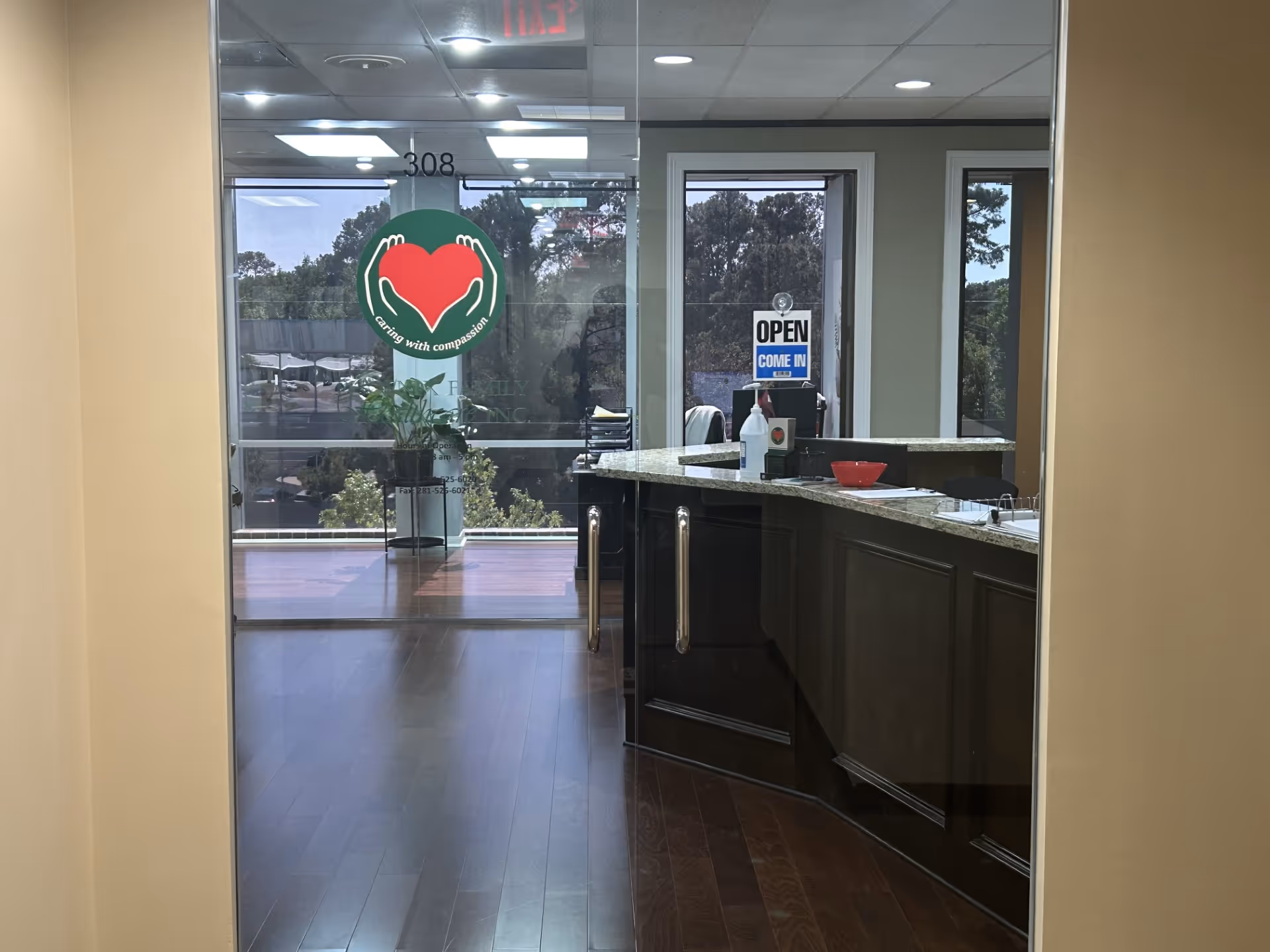 Lobby area with reception desk, glass doors, and a plant.
