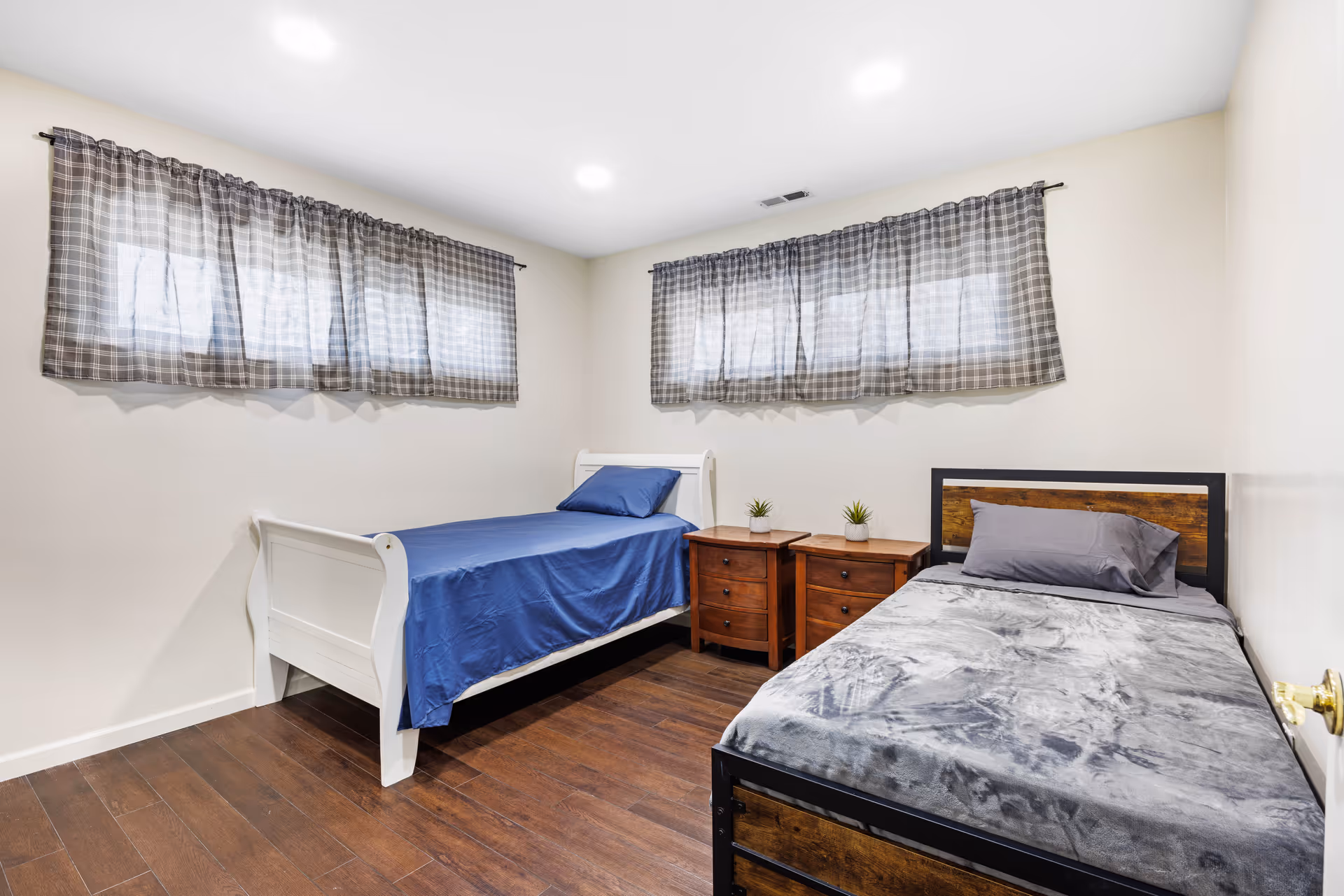 Two single beds with blue and gray blankets sit side by side in a tidy bedroom.