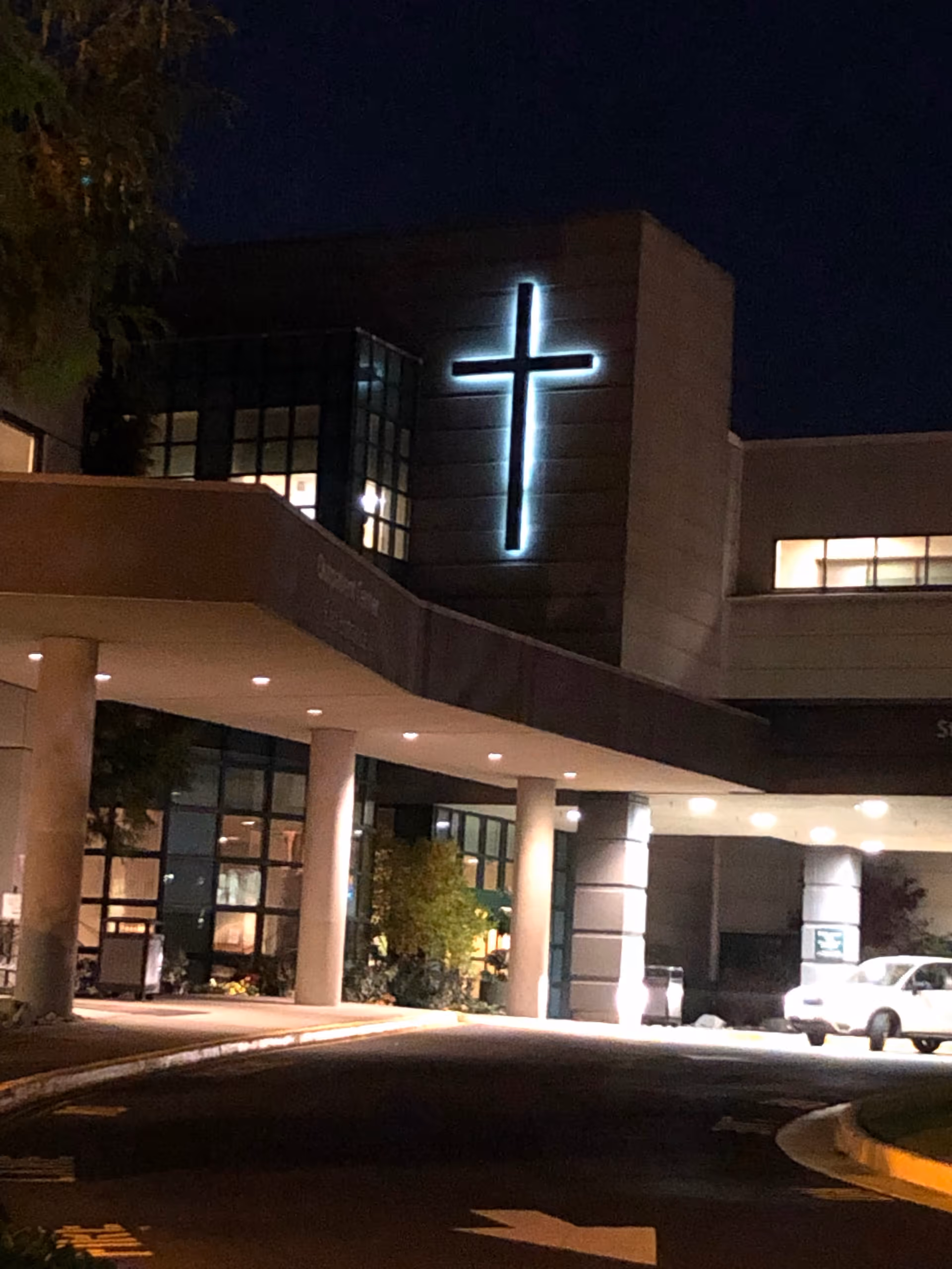 Night exterior of St. Francis Hospital with a glowing cross above the entrance.