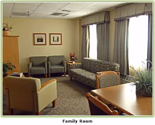 Interior family room with sofas, chairs, a table, curtains, and potted plants.
